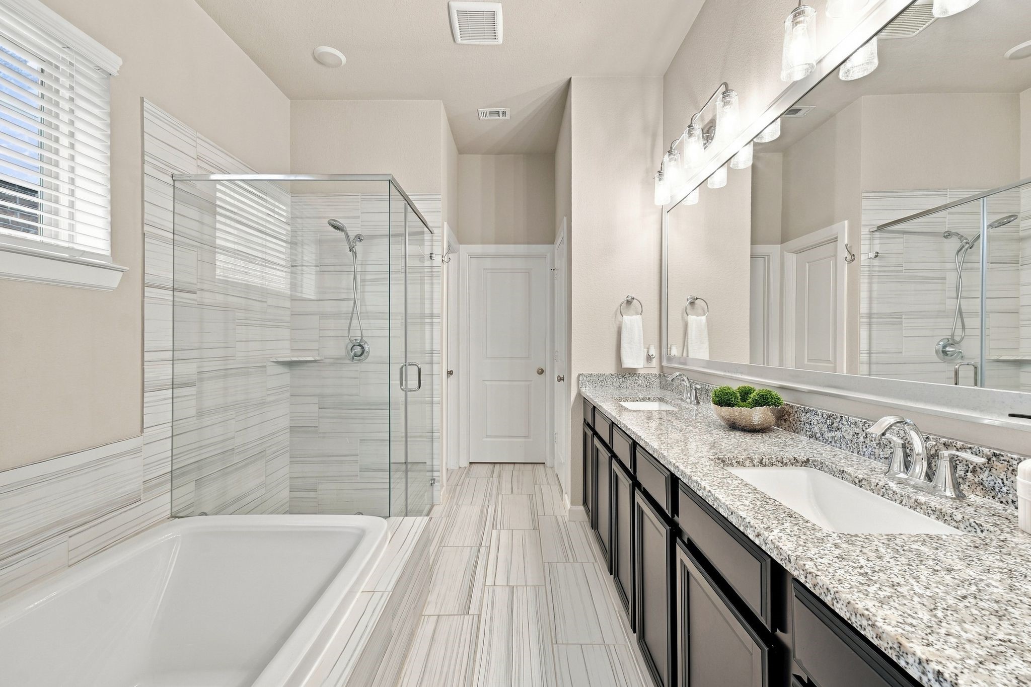 Dual vanity, a soaking tub, and a glass shower finished in floor to ceiling tile. This is where the day starts and ends right.