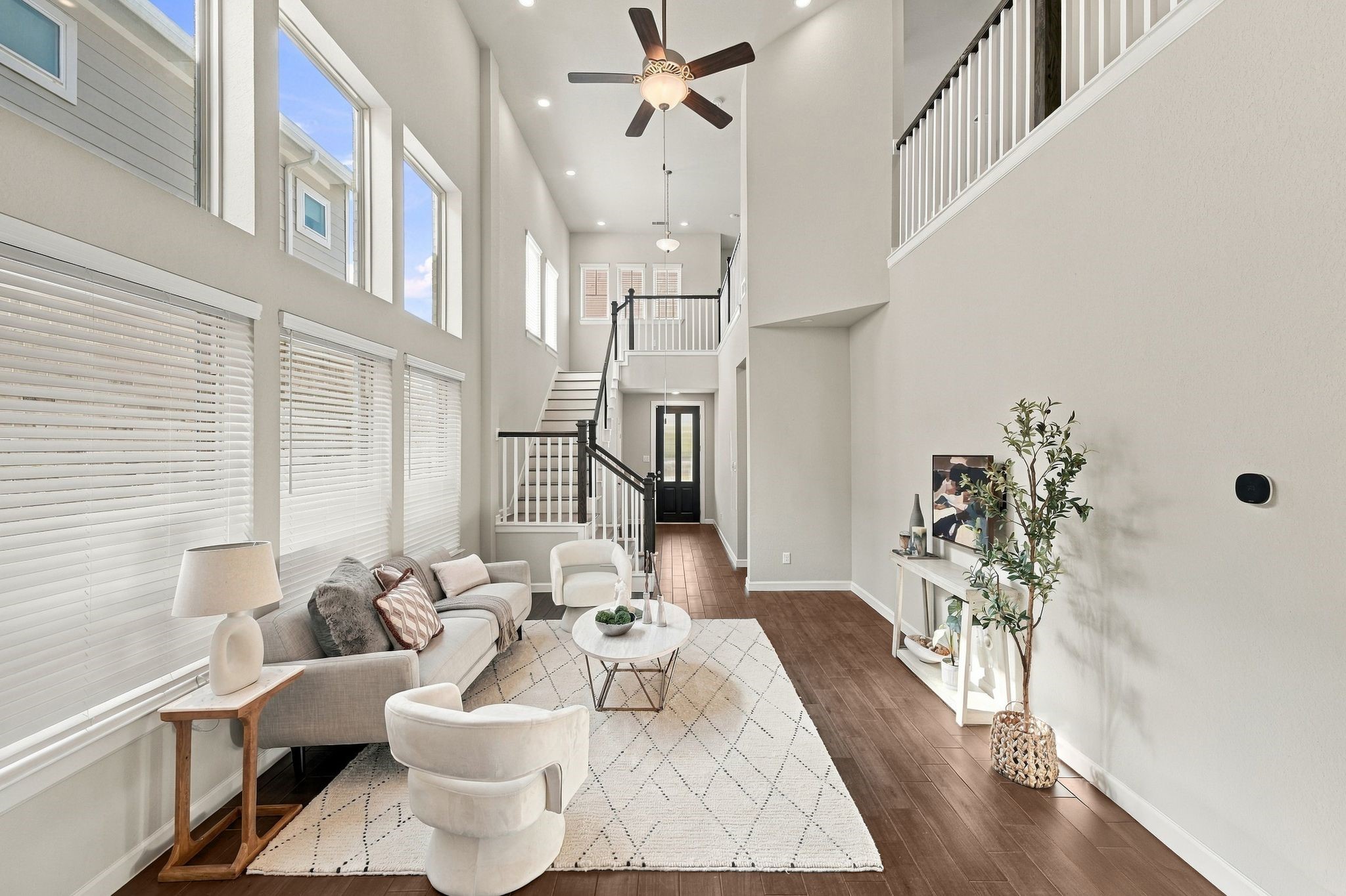 Family room with wall mounted TV space, console table, and view back toward the stairs and entry.