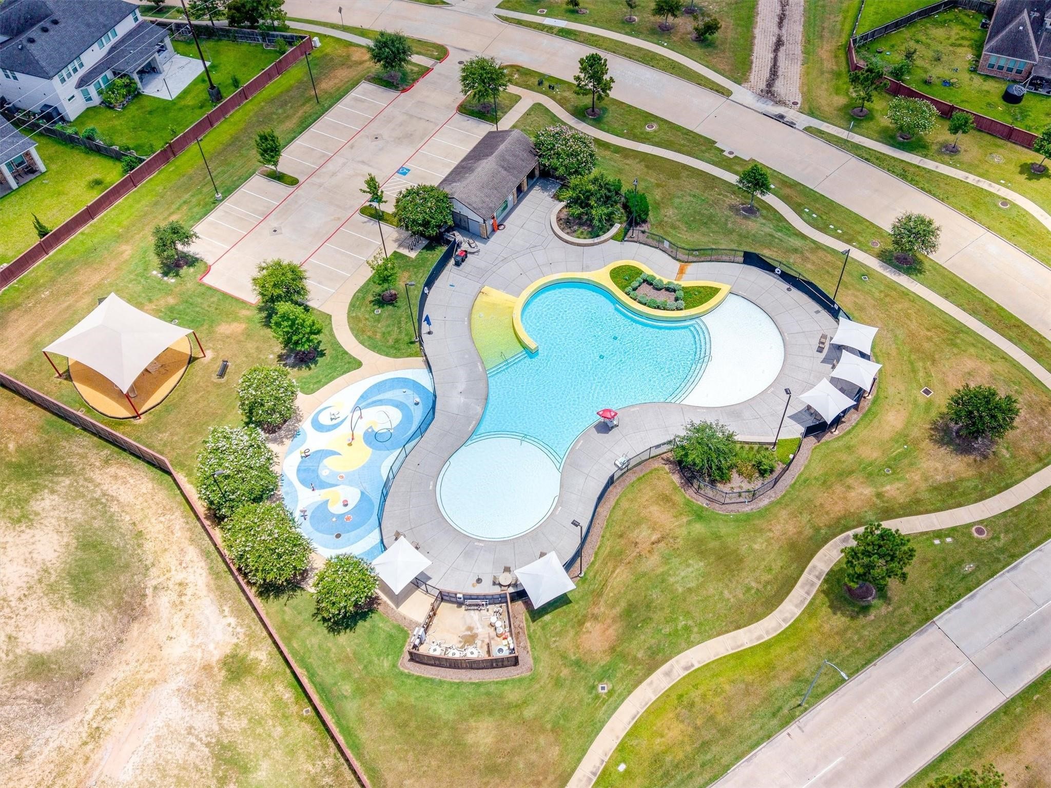 Aerial view of the community's resort style pool, splash pad, shaded cabanas, and clubhouse with dedicated parking.