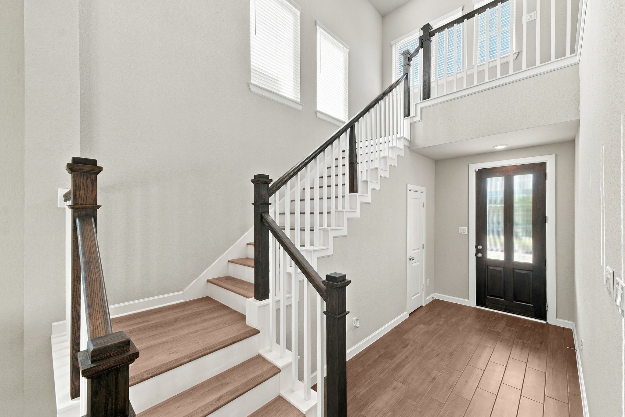 Warm wood tone stairs and a light filled foyer set the tone from the first step.