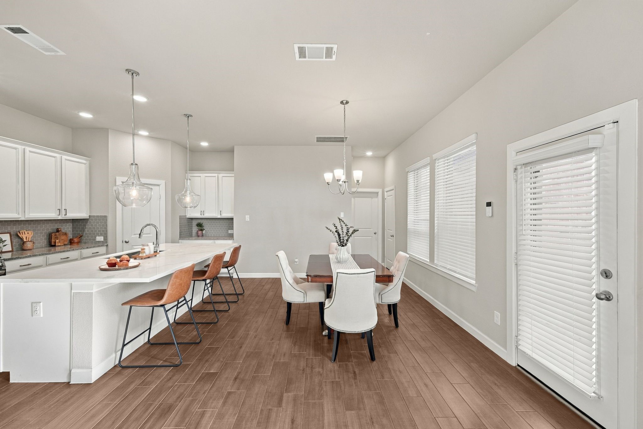 Kitchen island with bar seating opens to the dining table and a door leading out to the backyard patio.