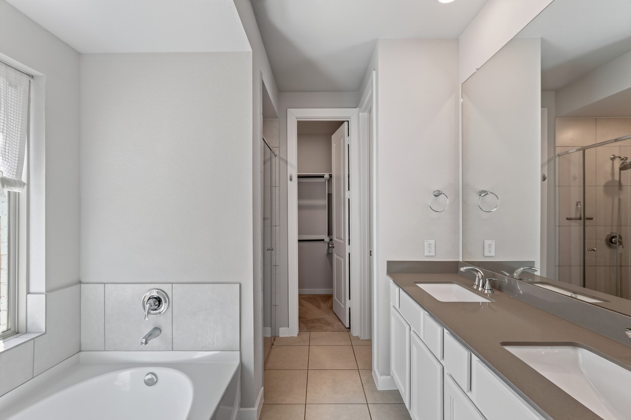 The primary bathroom delivers a spa-inspired experience, with a luxurious soaking tub, a stylish double vanity featuring dark countertops and crisp white cabinetry, and elegant modern fixtures  your personal retreat at the end of every long day.