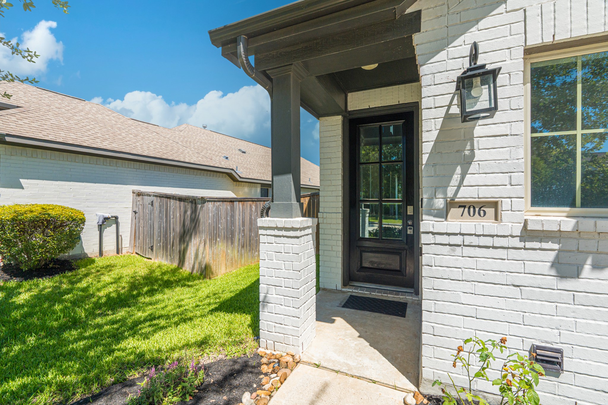 The covered front entry makes a stunning first impression  stone surround, dark paneled front door, and a warm lantern-style sconce light create an inviting arrival experience that sets the stage for the quality and style you'll find throughout the home.