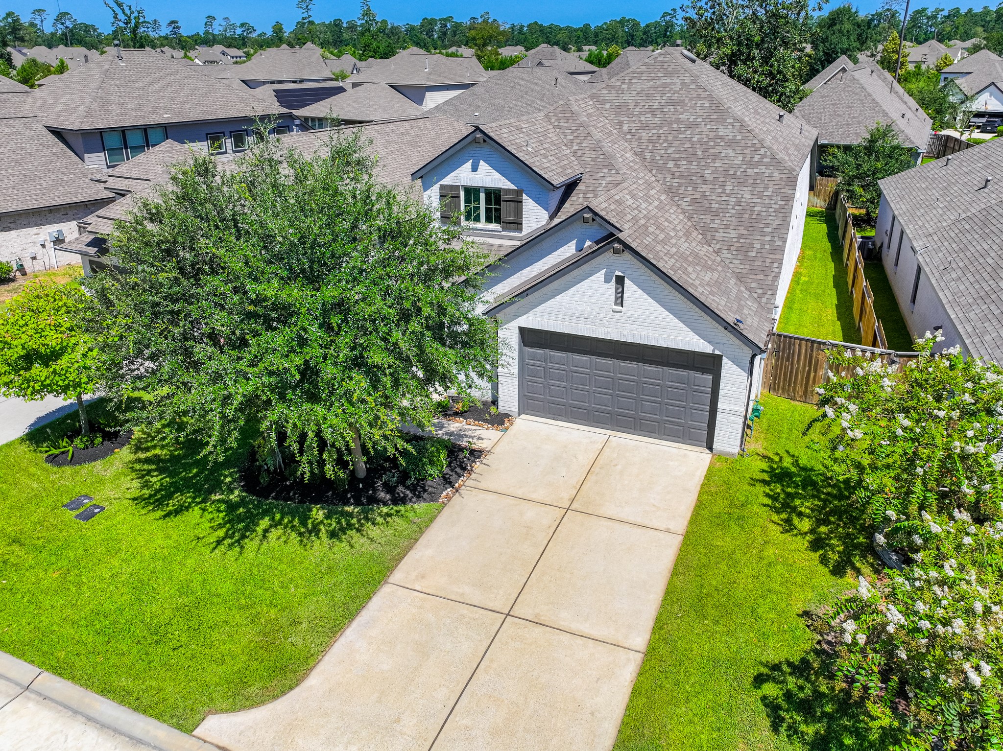 Bird's-eye aerial view of 706 Santa Elena Trail shows the home's generous lot, manicured green yard, two-car garage, and ideal location within Grand Central Park. The neighborhood's lush tree canopy and master-planned layout are clearly visible from above.
