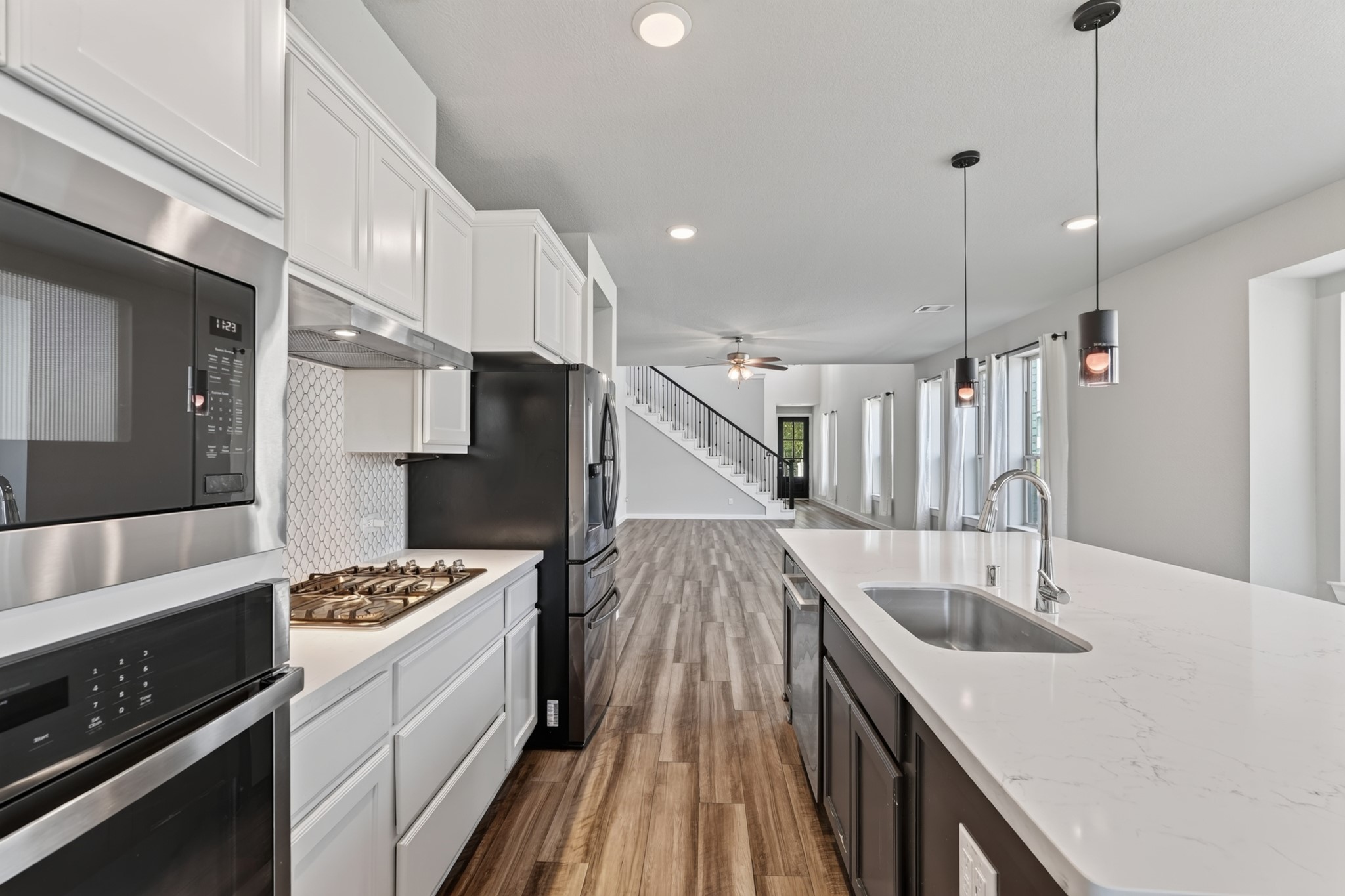 The kitchen's gas range sits perfectly between white cabinetry and the striking navy blue island, flanked by warm pendant lighting above. Every element of this kitchen was carefully designed for both outstanding daily function and timeless stylish appeal.
