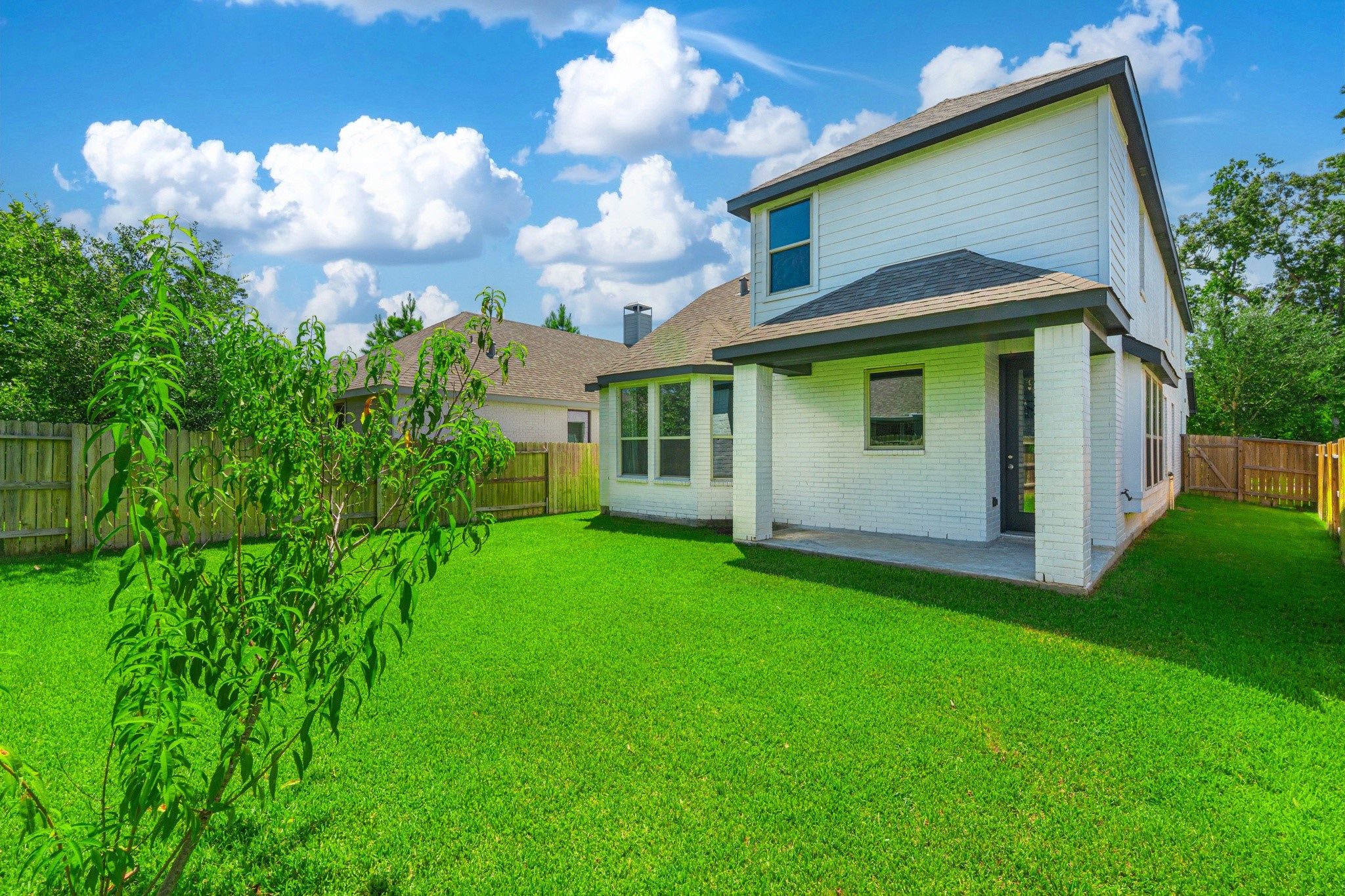 The rear exterior of 706 Santa Elena Trail showcases modern board-and-batten siding, clean architectural lines, and a lush green backyard with ample space for outdoor living. Move-in ready inside and out  this home is truly the complete package.