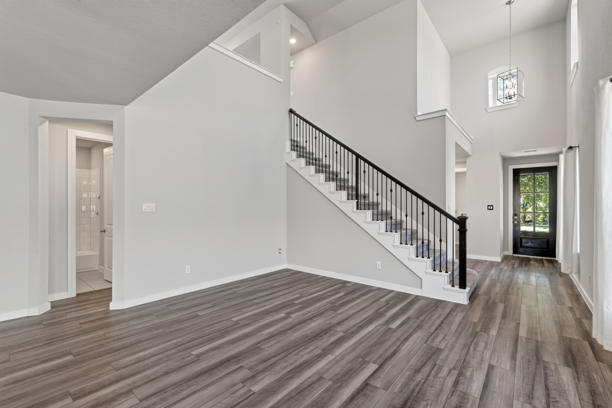 The grand staircase is a true architectural highlight  featuring elegant black iron balusters, crisp painted risers, and rich dark hardwood flooring at the base. A sophisticated design detail that elevates the character and quality of the entire main floor.