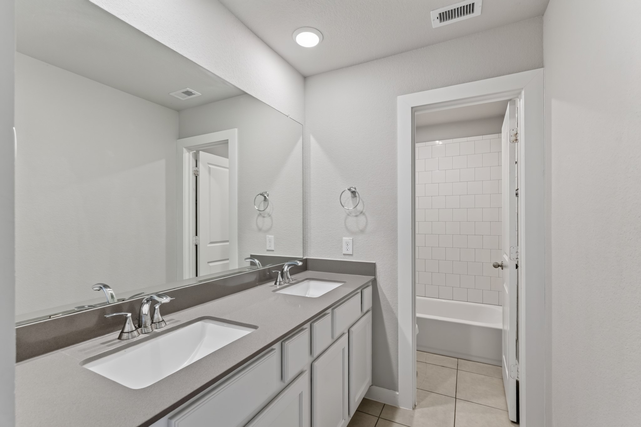 The upstairs shared bathroom features a double-sink vanity with a dark countertop and mirror  ideal for busy morning routines when multiple family members need the space. Functional, stylish, and easy to maintain, it serves the secondary bedrooms beautifully.