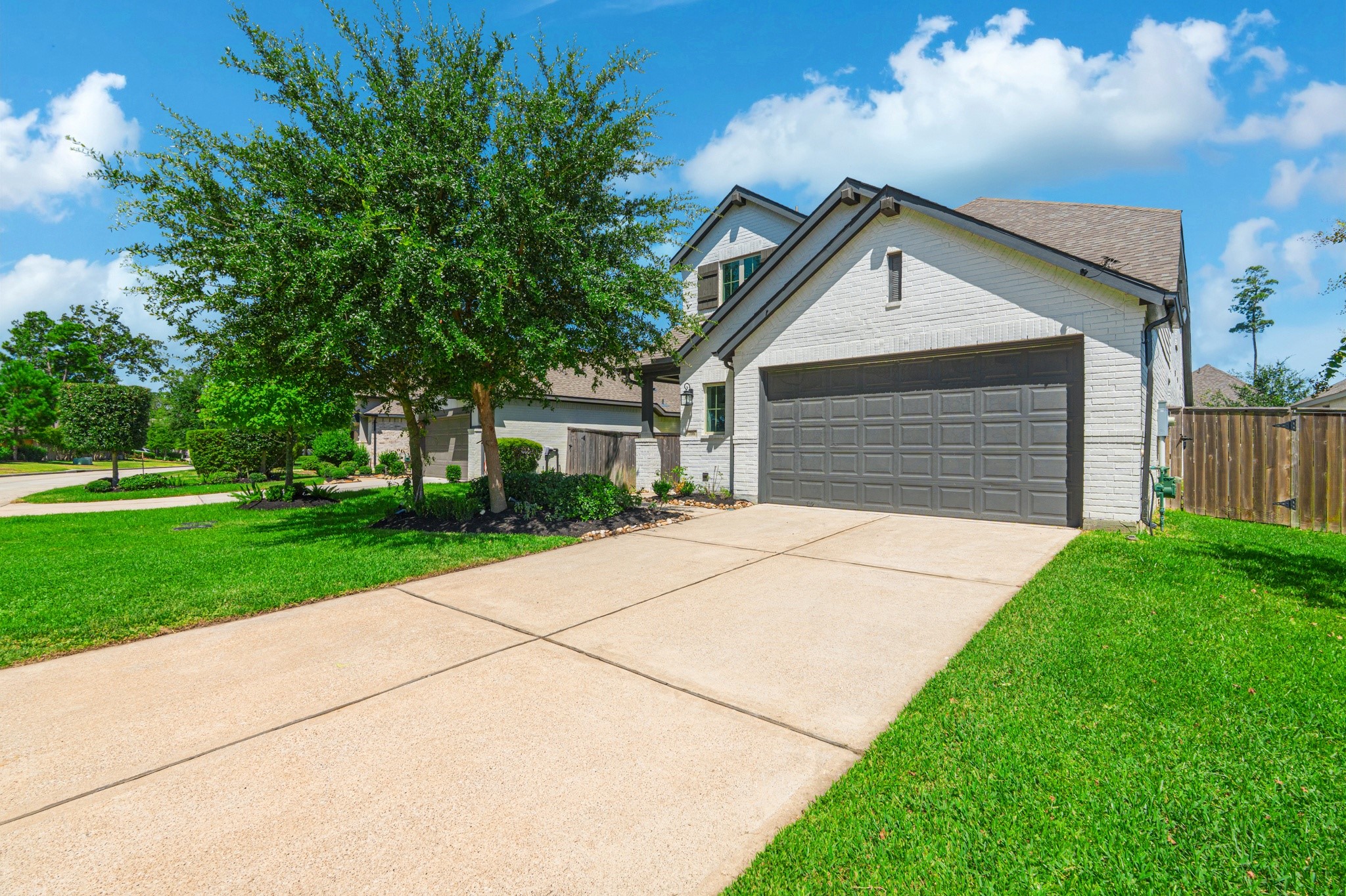 Another look at this home's beautiful front elevation, highlighting the clean modern lines, stone accent details, manicured front lawn, and wide two-car garage. Grand Central Park's tree-lined streets make every arrival feel like coming home.