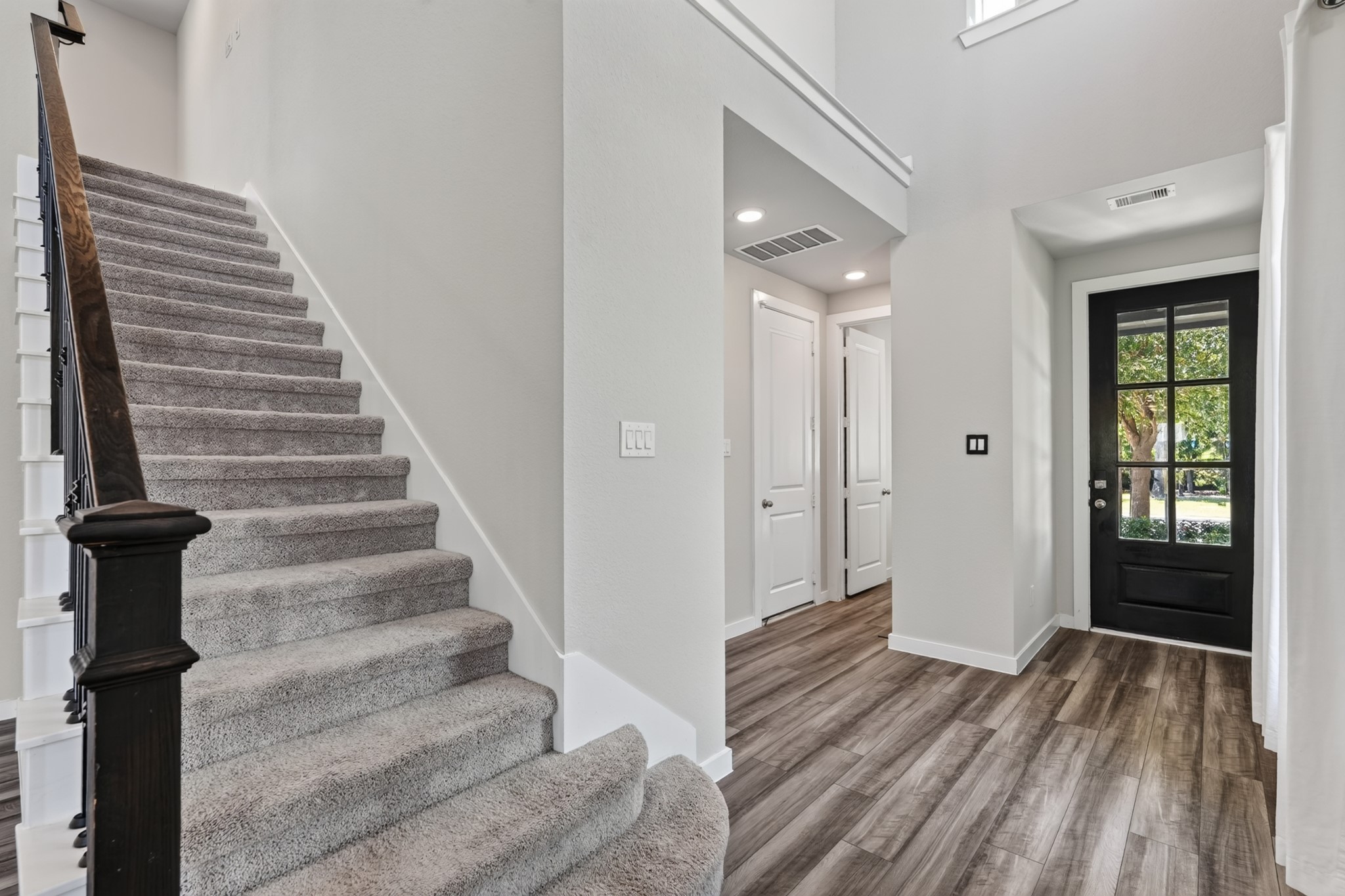 A view toward the graceful staircase from the main floor puts the beauty of the black iron balusters and the craftsmanship of this design detail on full display. Together, the staircase and entry set a tone of quality and elegance throughout the entire home.
