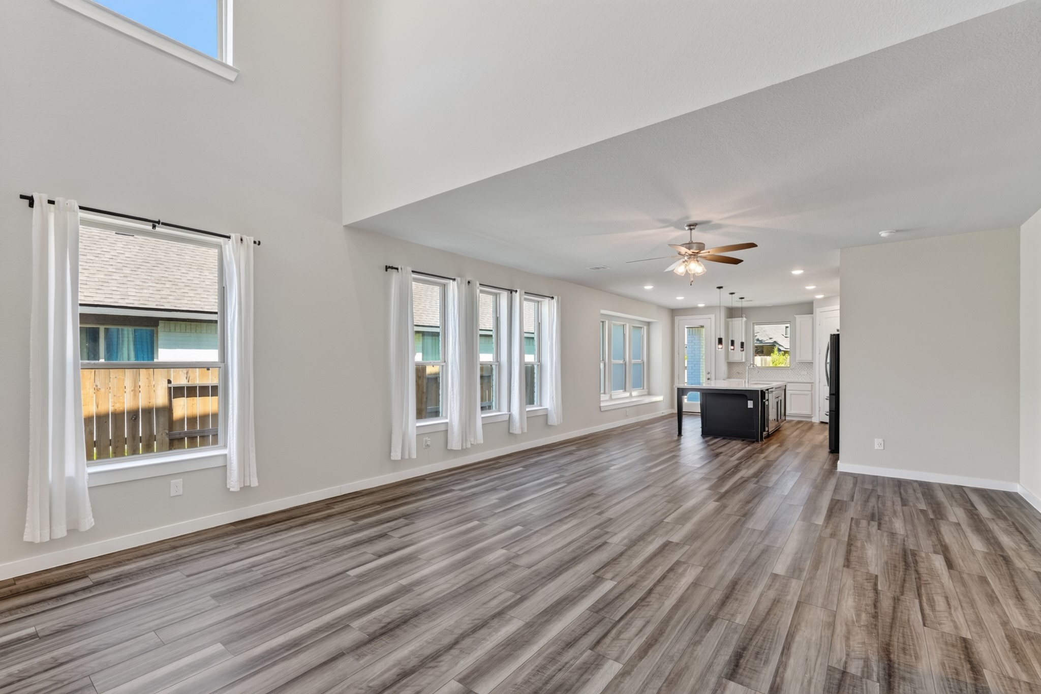 The family room is flooded with natural light from oversized windows, with a ceiling fan overhead and gorgeous dark hardwood floors below. Open, bright, and generously sized  this living space feels both expansive and naturally comfortable every single day.