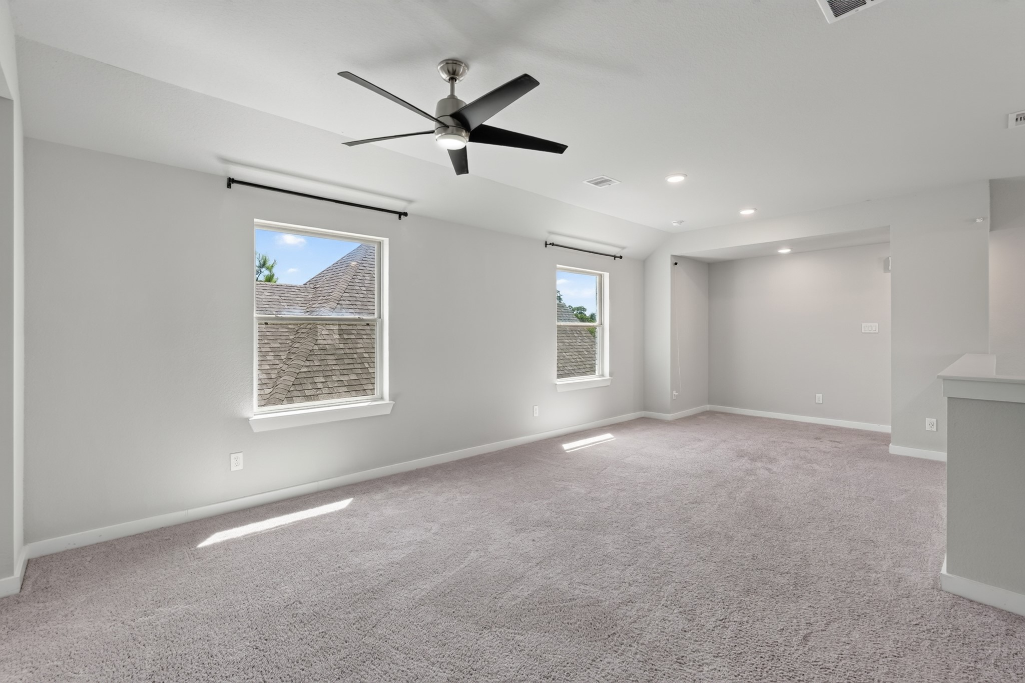 Another view of the generous upstairs game room shows just how versatile and spacious this bonus area truly is. A ceiling fan, plush carpet, and neutral walls make this room a natural gathering spot for activities, entertainment, and everyday fun upstairs.