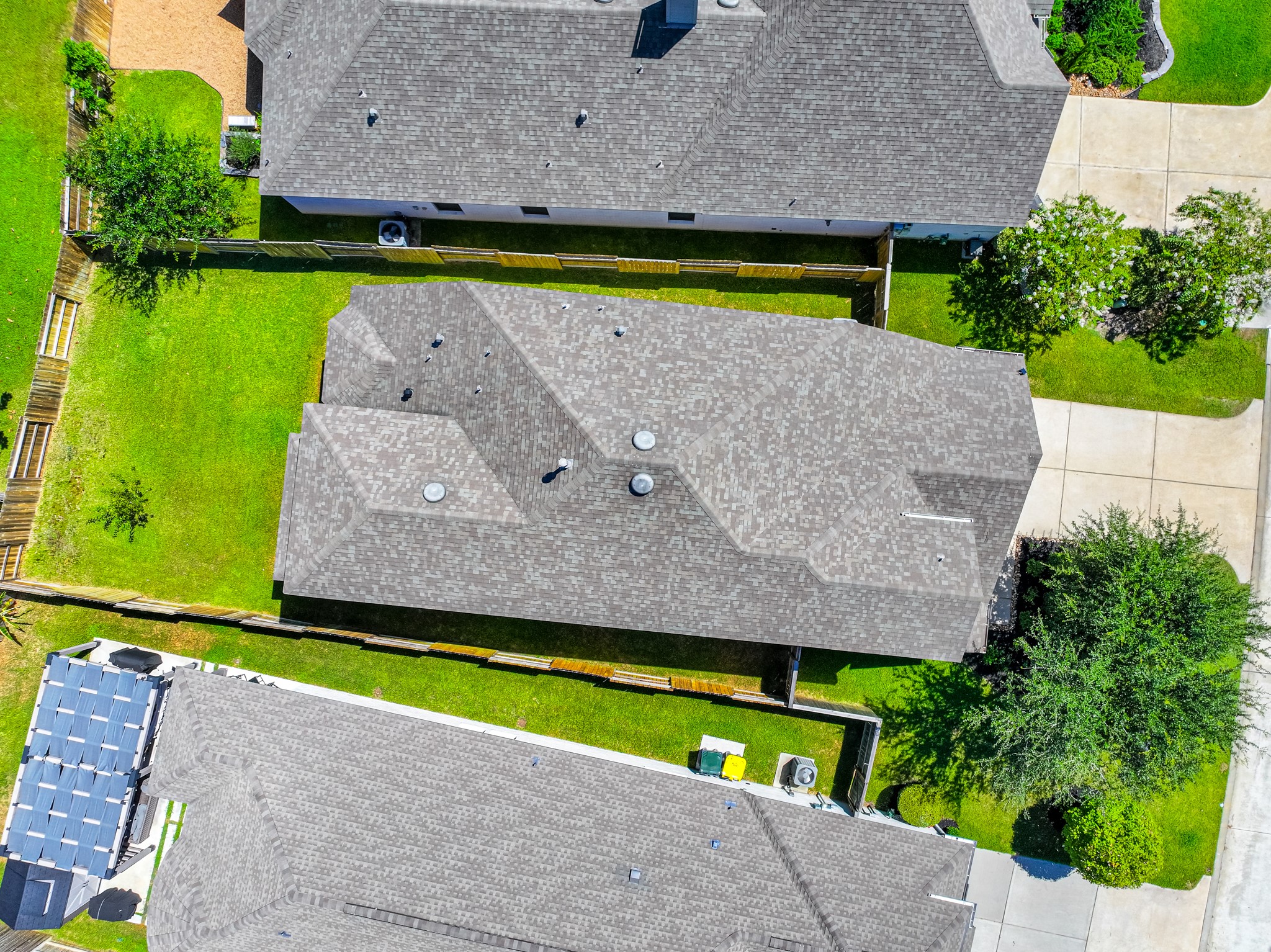 Aerial view of 706 Santa Elena Trail shows the home's roofline, two-car garage, backyard, and beautiful surroundings within Grand Central Park. The neighborhood's green canopy, winding streets, and thoughtful master-planned community design are clearly visible.