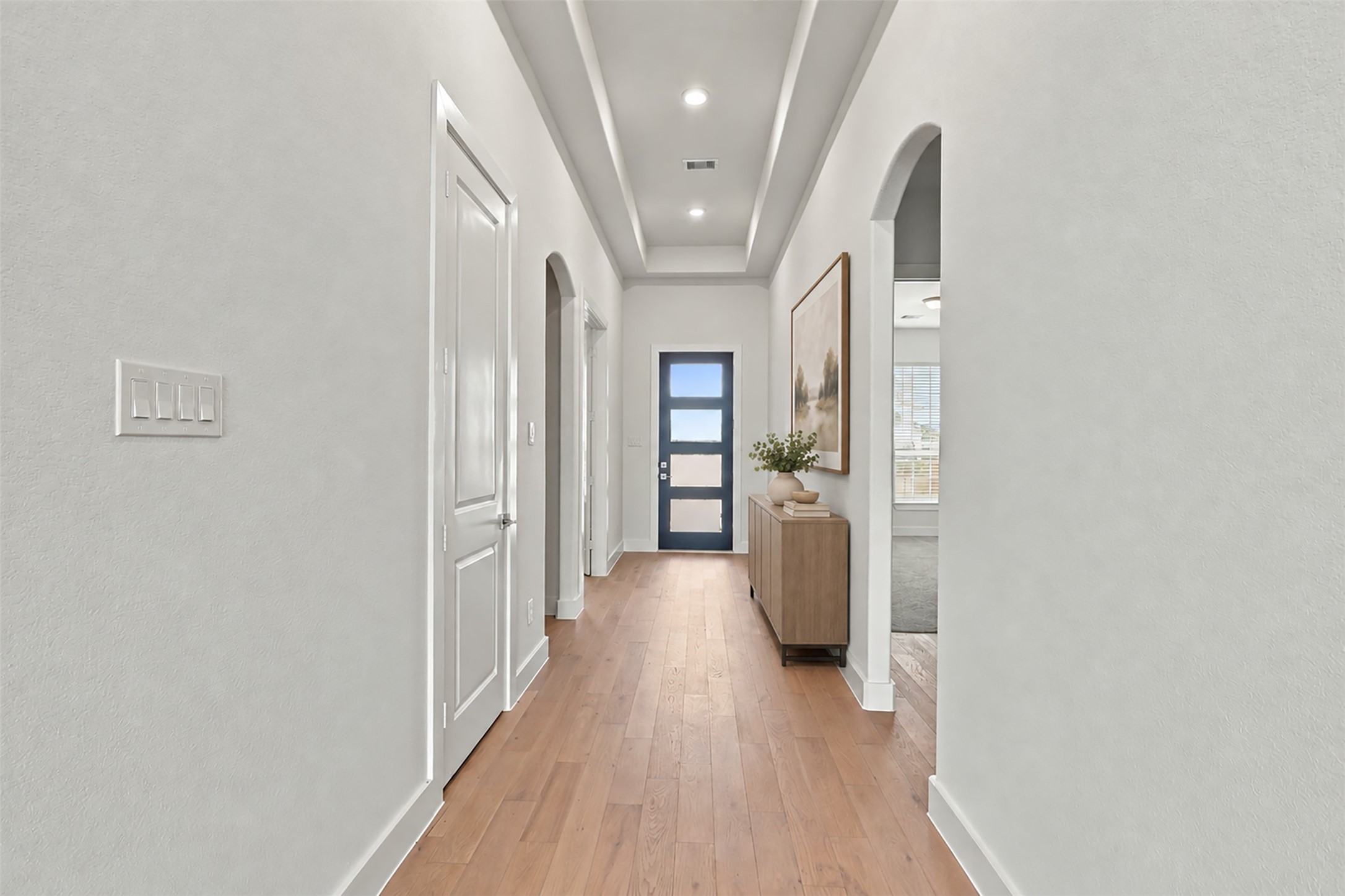A BEAUTIFUL WELCOME HOME! Gorgeous engineered wood flooring extends throughout this inviting hallway, creating a warm, cohesive look! Soft neutral walls, recessed lighting, and elegant ceiling details enhance the bright, open atmosphere! The arched architectural detail adds a touch of character as you make your way through this THOUGHTFULLY DESIGNED home! **Photo is Virtually Staged**