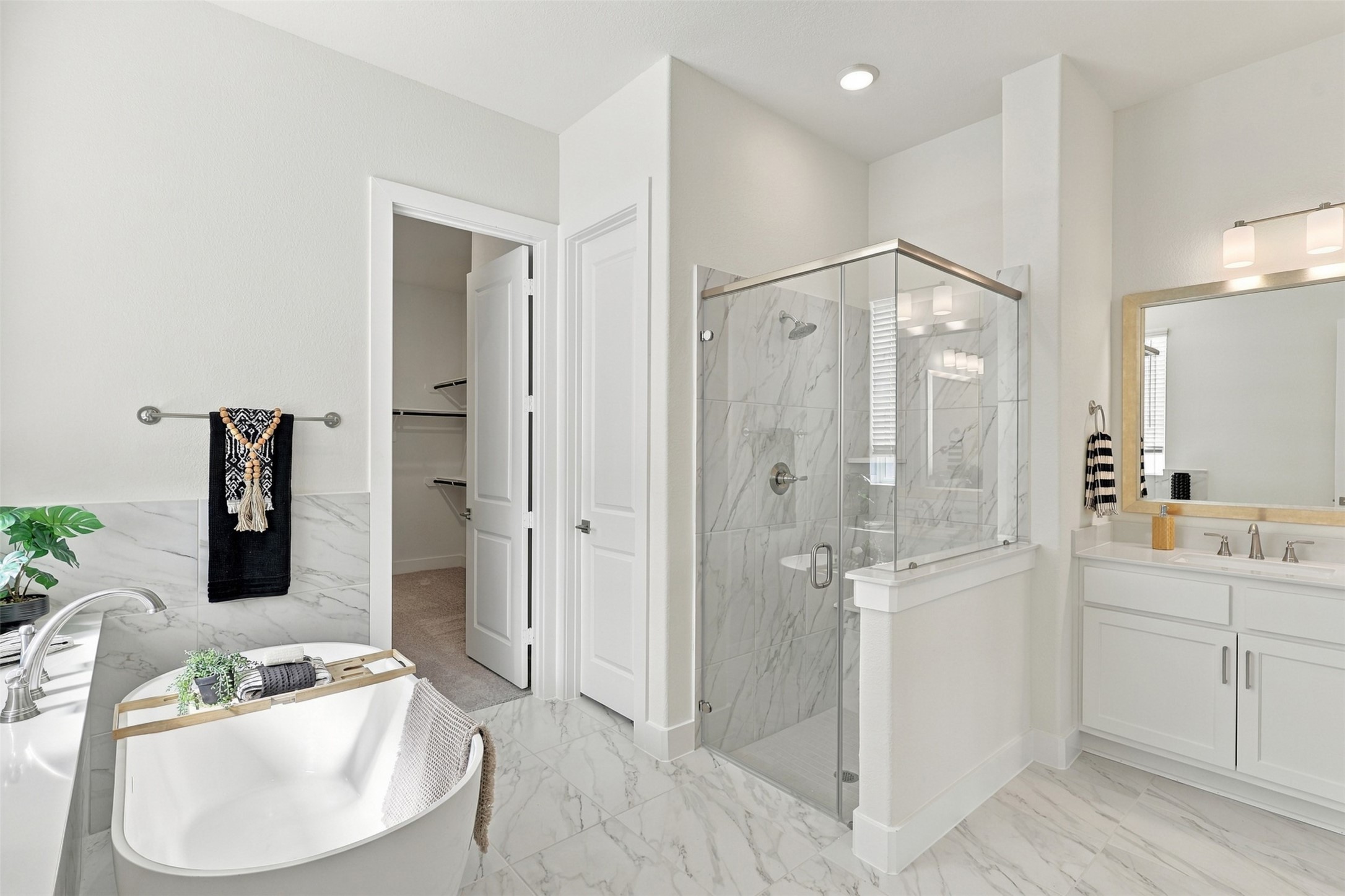 STEP INTO YOUR OWN PRIVATE SPA! This SPECTACULAR primary bathroom offers the best of both worlds with a relaxing soaking tub, separate glass-enclosed shower, and an expansive double-sink vanity! Beautiful tile flooring, crisp white cabinetry, and bright finishes create a clean, elegant atmosphere! What a WONDERFUL way to start and end your day!