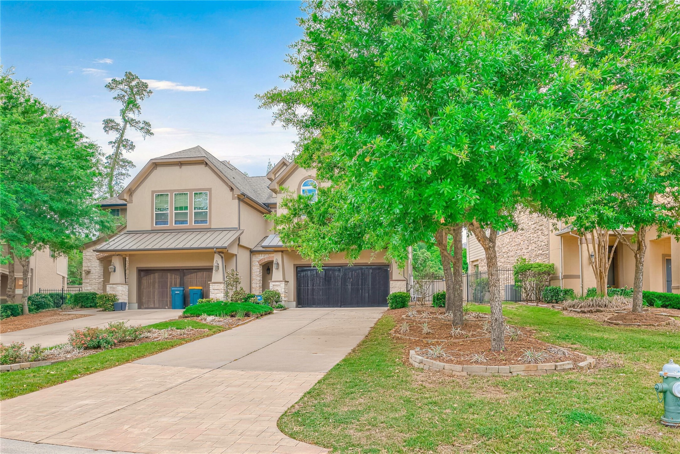 Charming two-story home with a spacious driveway, lush landscaping, and mature trees offering ample shade and curb appeal.