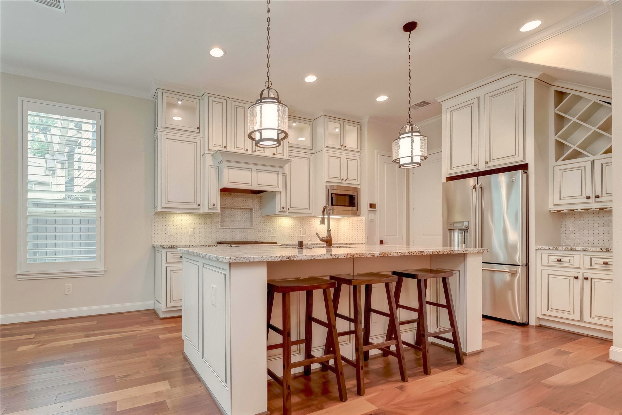 Stunning kitchen with elegant white cabinetry, granite countertops, and a spacious island with seating. Stainless steel appliances and pendant lighting create a perfect blend of style and functionality.