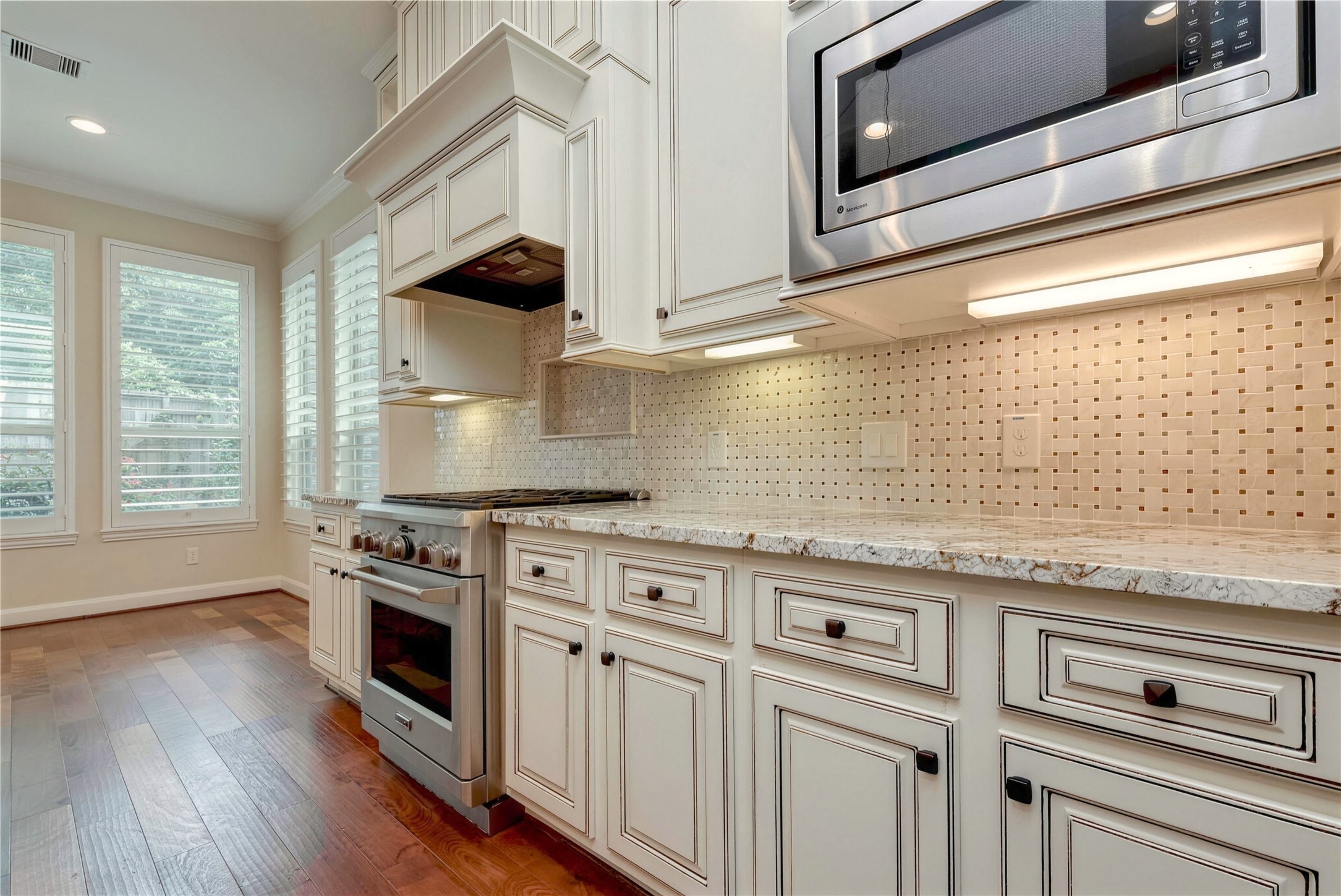 Elegant kitchen with custom cabinetry, granite countertops, and stainless steel appliances, bathed in natural light from large windows.