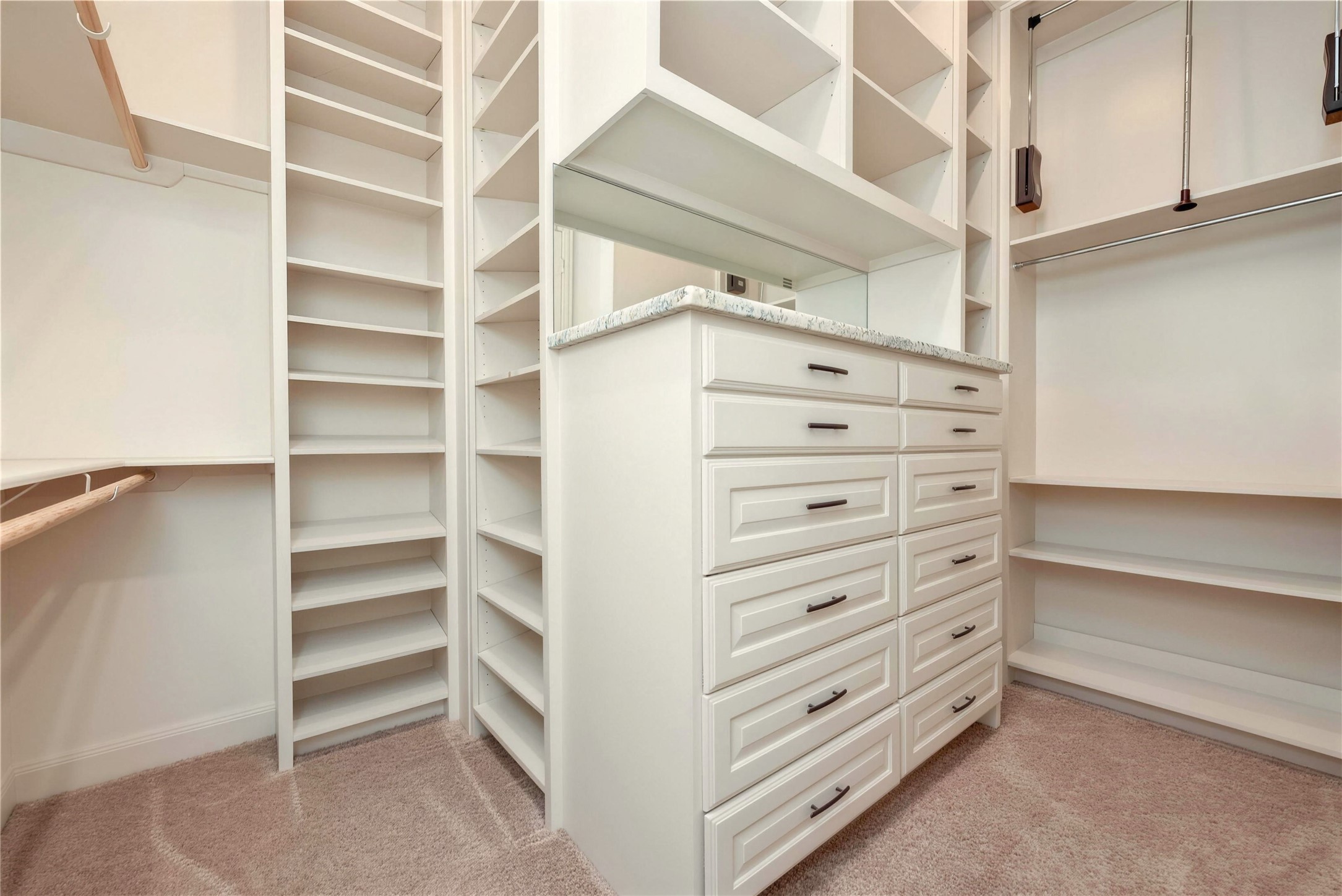 Spacious walk-in closet featuring custom built-in shelving, ample drawer storage, and a sleek countertop for organization and convenience.