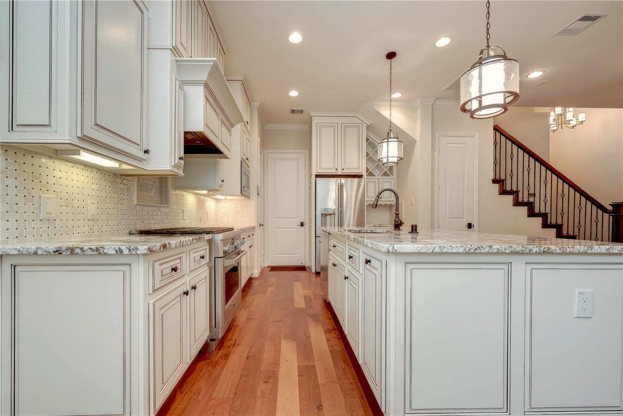 Elegant kitchen featuring custom cabinetry, granite countertops, and a spacious island with pendant lighting.