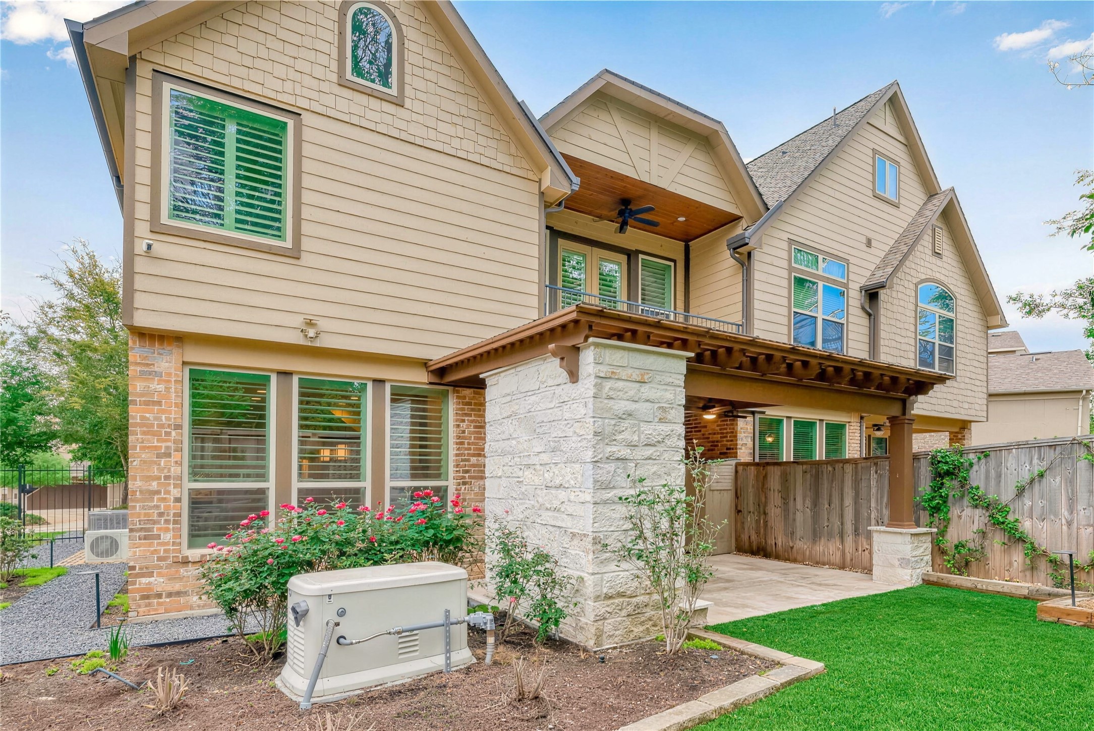 Charming two-story home featuring a spacious patio, beautiful brick and stone exterior, and lush landscaping. Perfect for outdoor entertaining and relaxation.