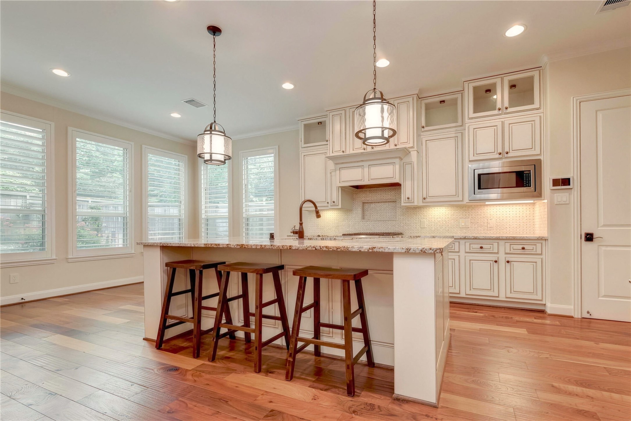Bright and inviting kitchen with elegant cabinetry, a spacious island with seating, and large windows providing ample natural light.