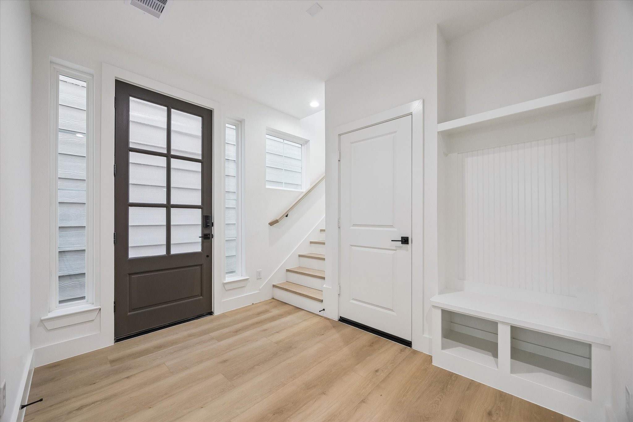 Welcoming entry with tall door, stair detail, and built-in drop zone Welcoming entry with tall door, stair detail, and built-in drop zone