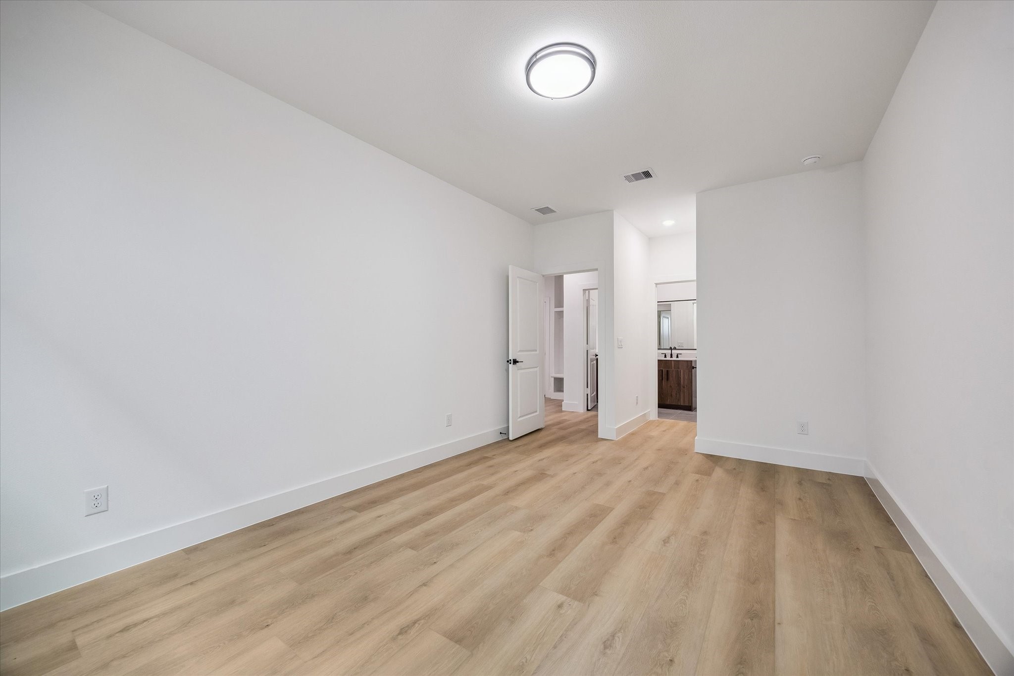Light-filled bedroom with clean flooring and flexible furniture placement