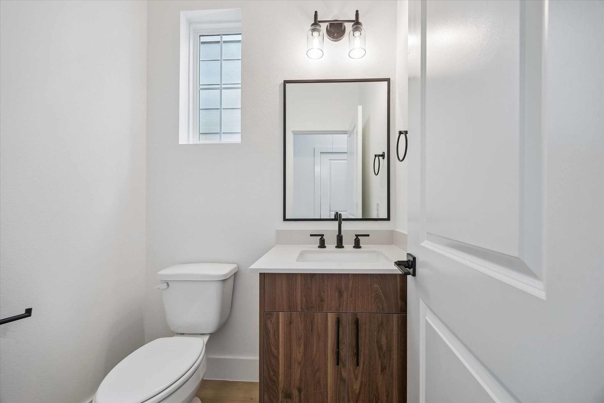 Stylish powder bath with floating-style vanity and framed mirror