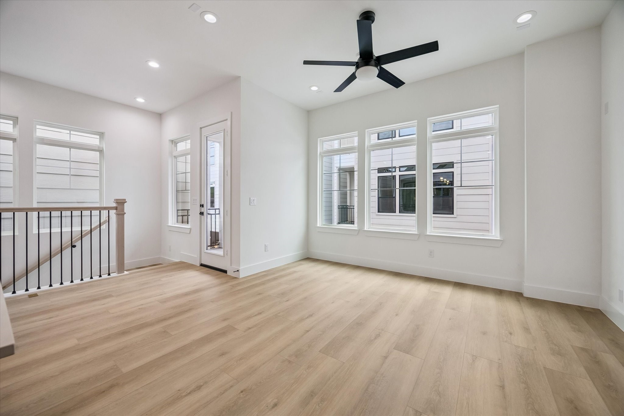 Comfortable living area with ceiling fan, windows, and warm flooring