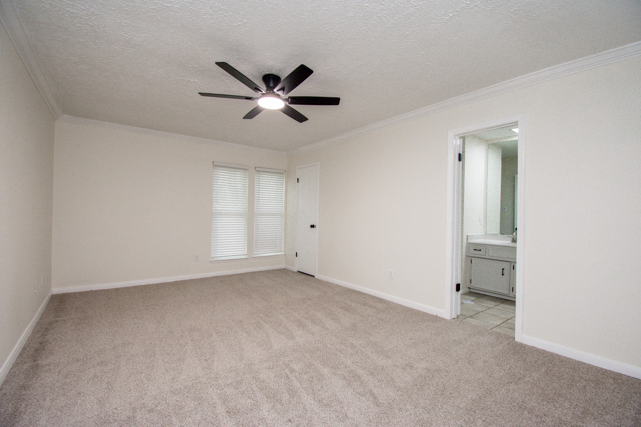 Primary bedroom with ceiling fan, sitting area and fresh paint