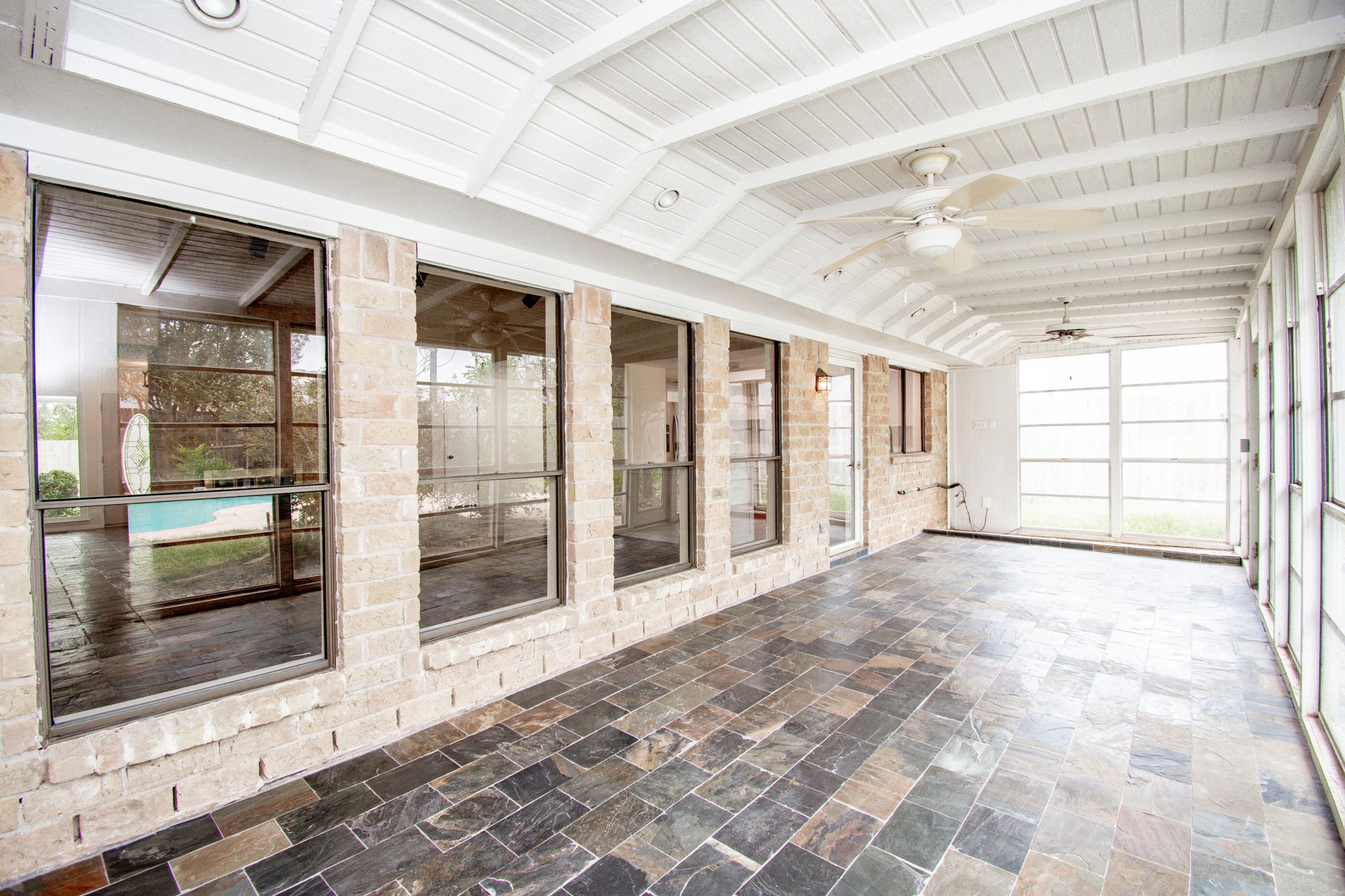 Enclosed sunroom with slate tile, ceiling fans and planter space for the plant lover