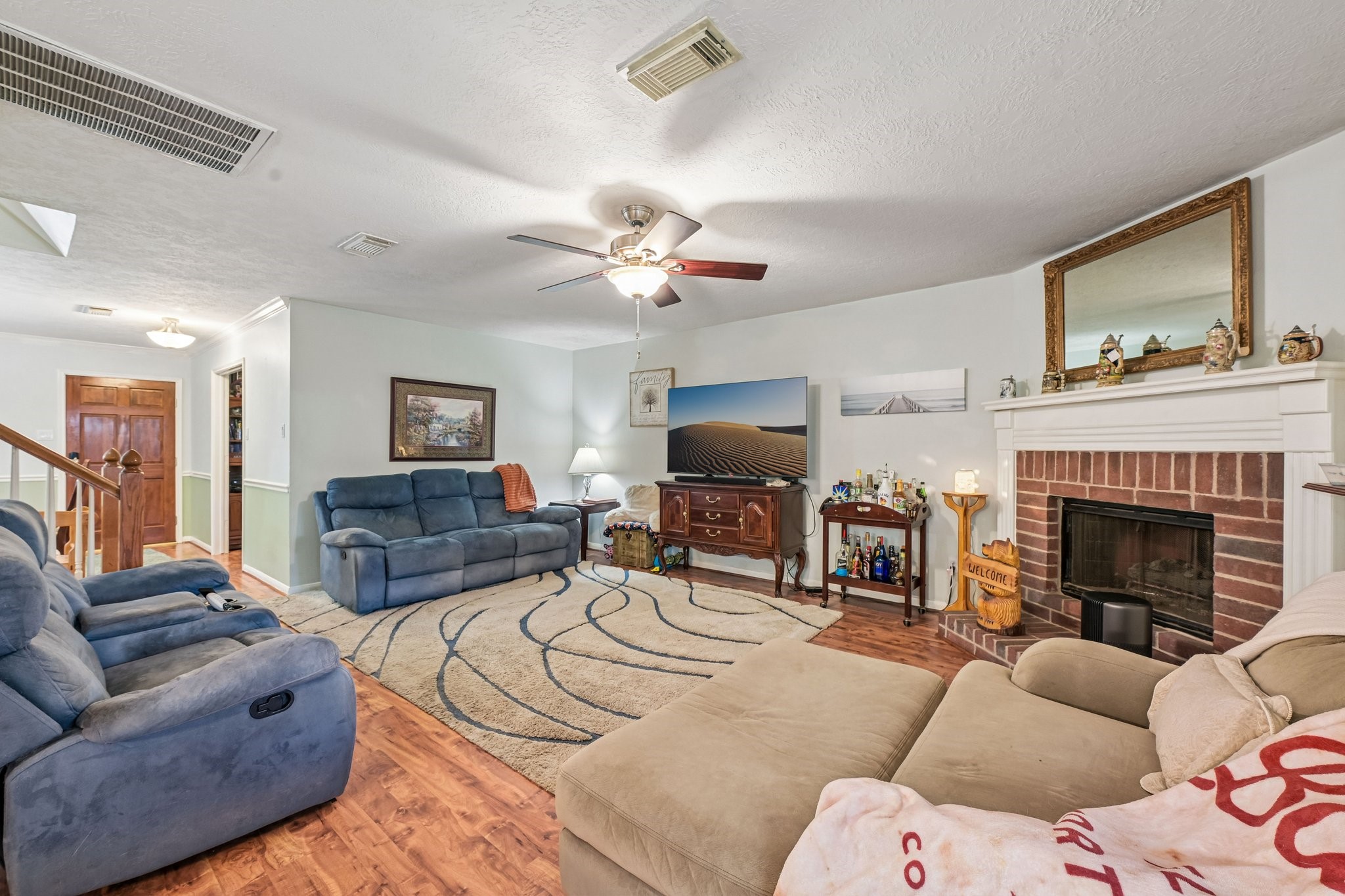 Bright living space highlighting the cozy corner fireplace, mantle, and direct views to the entry hall.