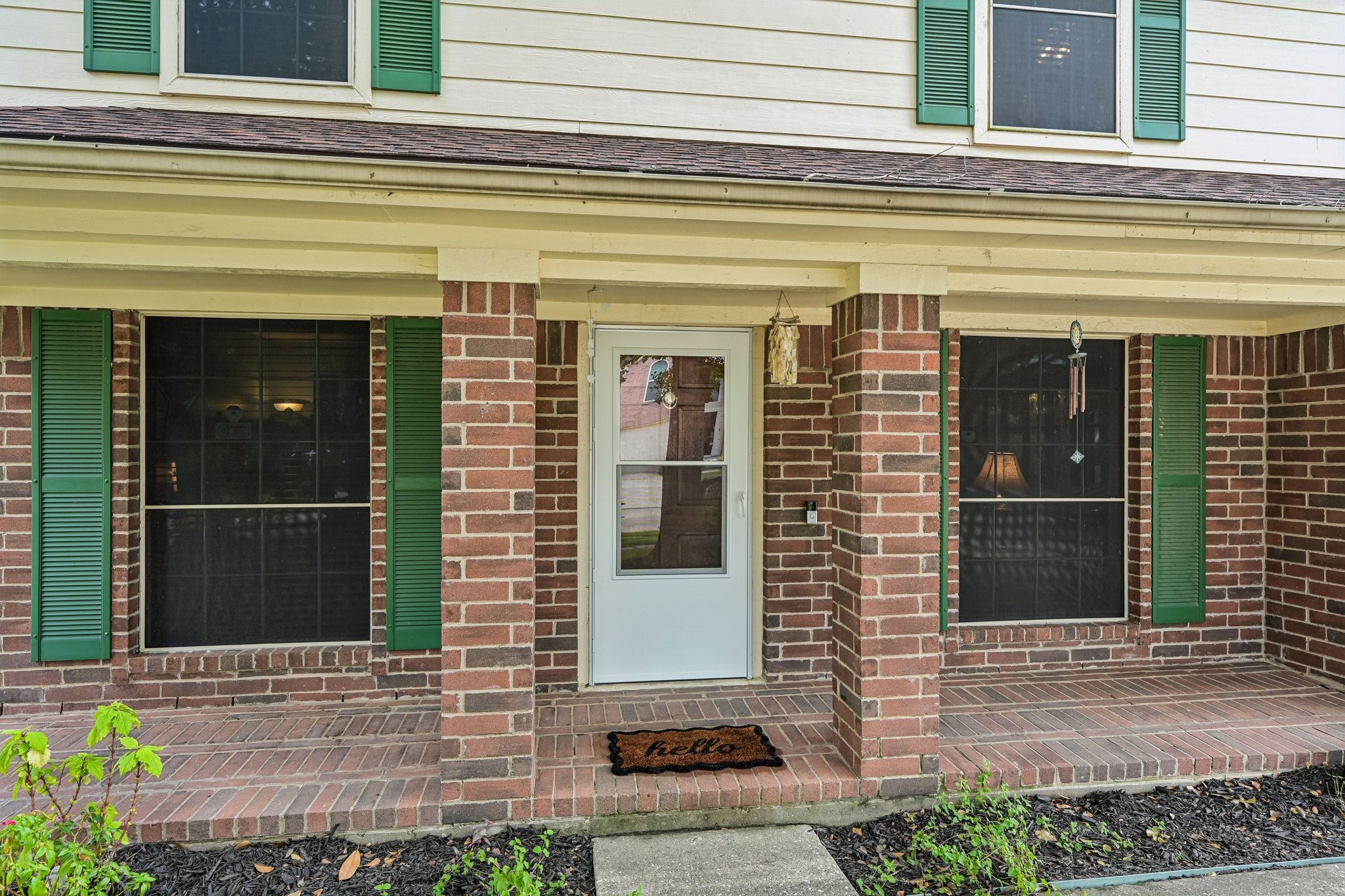 Welcoming front elevation displaying beautiful curb appeal, green window shutters, dark mulch landscaping beds, and a covered front entry. Welcoming front elevation displaying beautiful curb appeal, green window shutters, dark mulch landscaping beds, and a covered front entry.