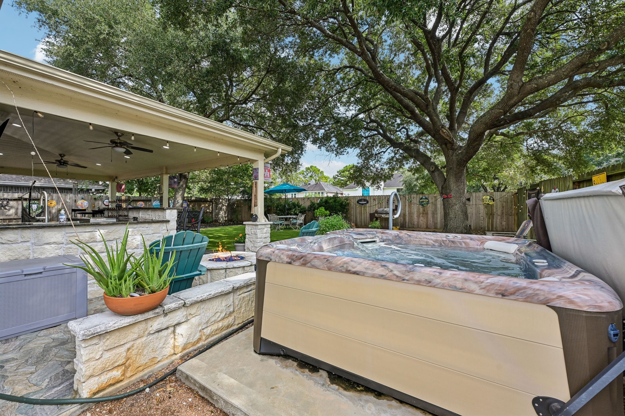 Premium 2022 Hot Spring Vanguard hot tub set on a dedicated concrete pad adjacent to the stone fire pit and covered patio