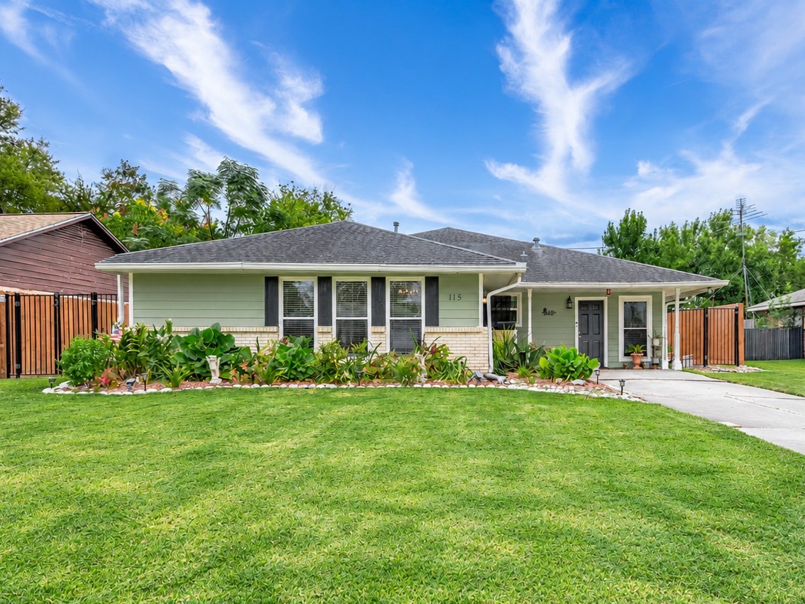 Brick and siding exterior with full gutters, flower beds and a fenced yard.