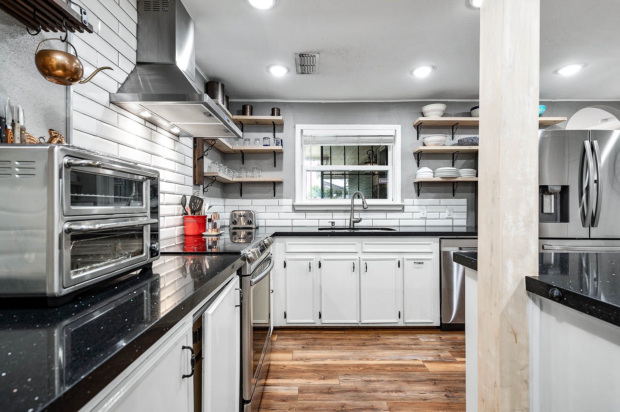 Slide-in electric range with stainless vent hood and subway tile backsplash.