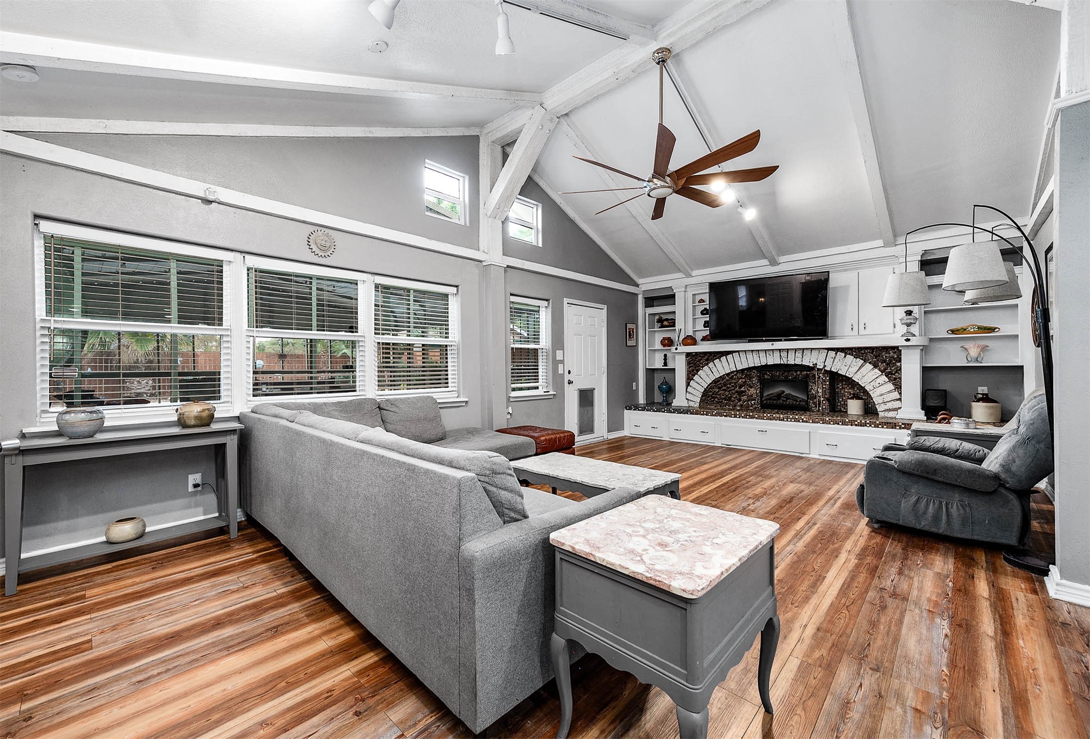 Vaulted living room with electric fireplace, open to the kitchen and breakfast area.