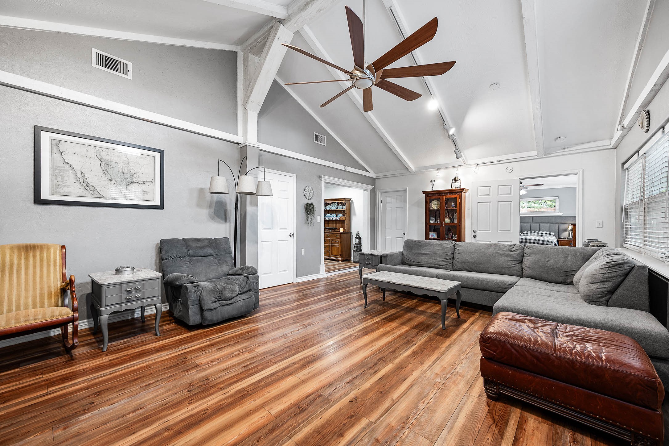 Living room with vaulted ceiling, ceiling fan and lots of natural light.