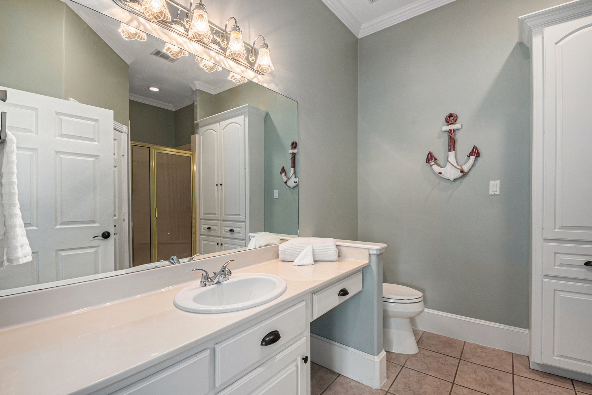 This secondary bathroom in the guest house offers a glass-standing shower, vanity seating, and lots of storage space.