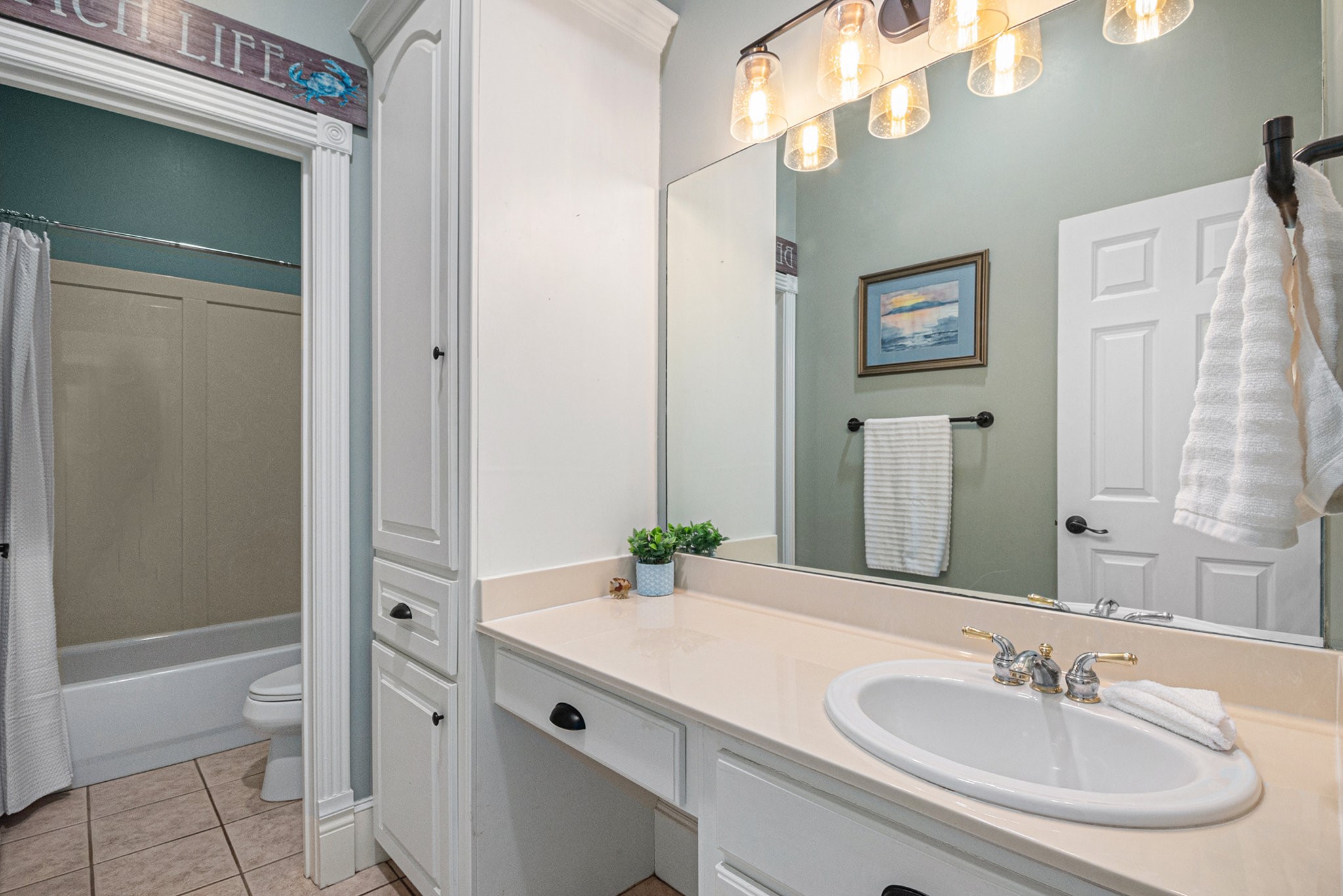 Full bathroom in the guest house features a combination tub and shower, vanity seating, and lots of storage space.