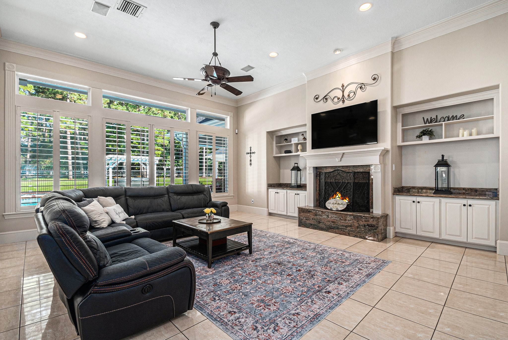 The spectacular main living room presents high ceilings, gorgeous built-ins, a cozy fireplace, and great views of the backyard.
