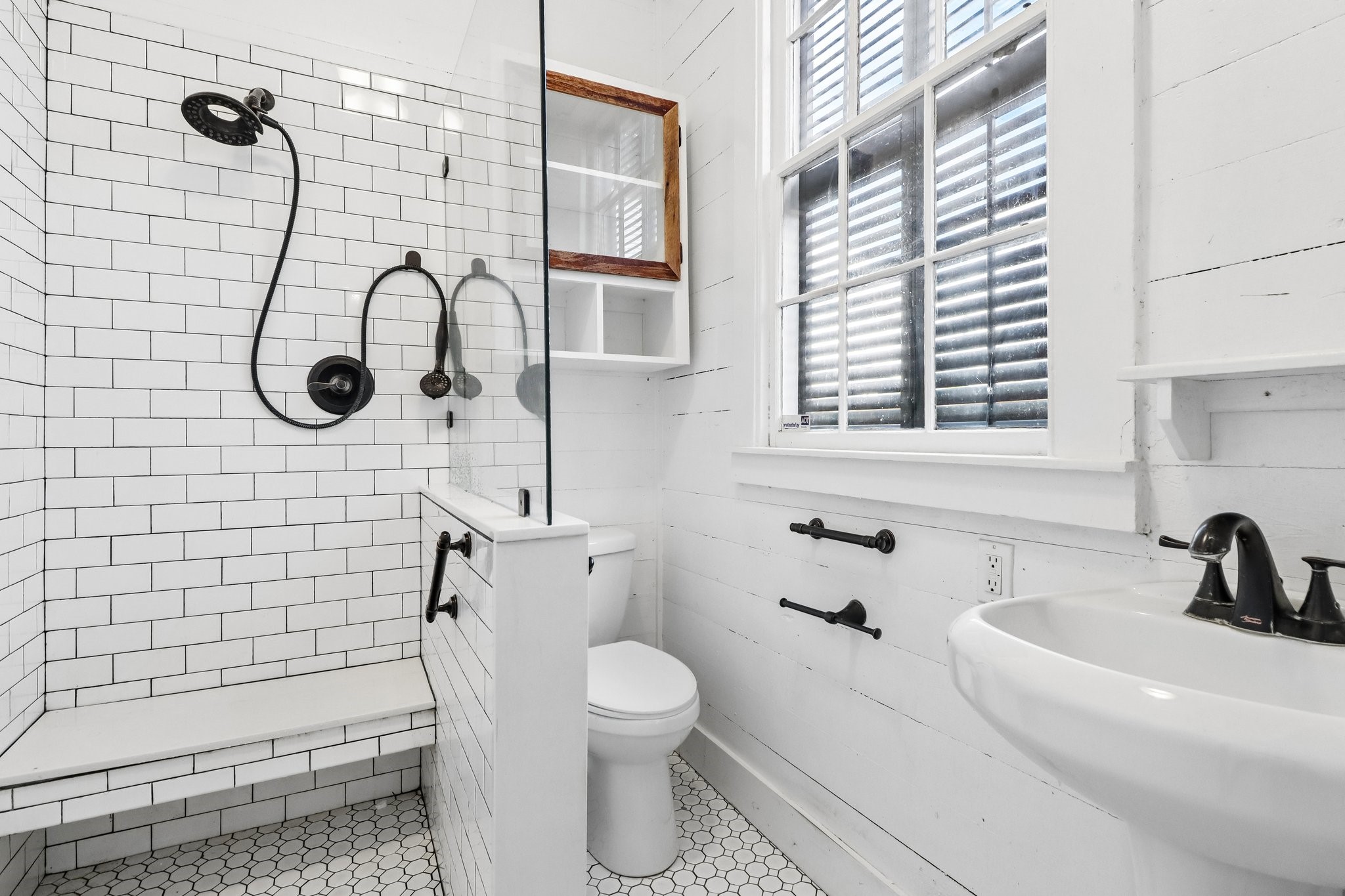 A bathroom with a freestanding clawfoot tub, pedestal sink and white finishes.