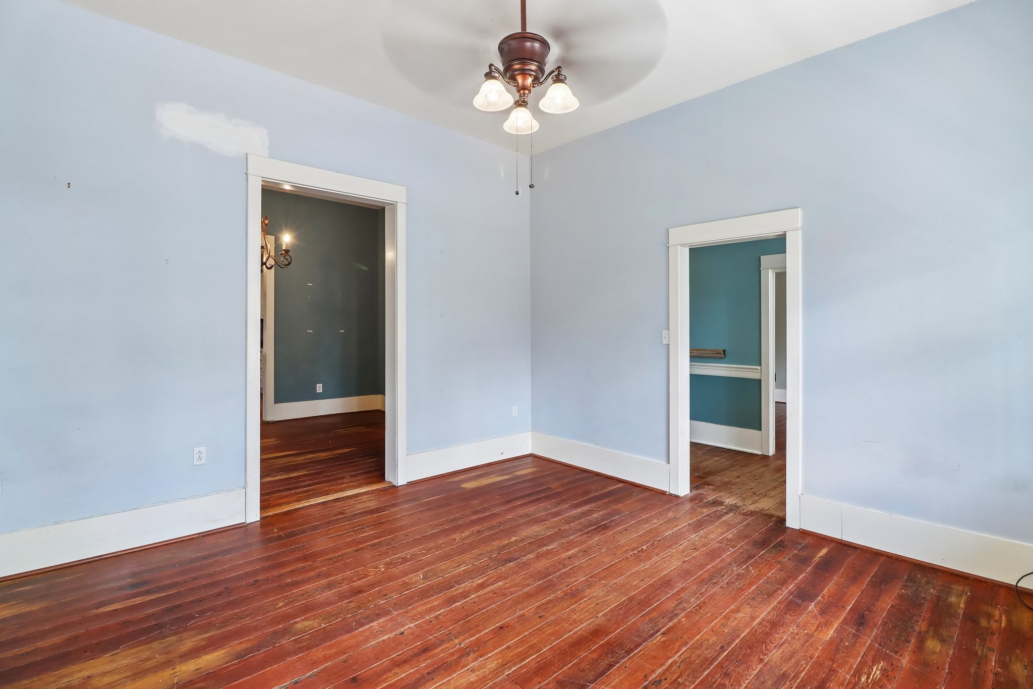 Wood flooring and a ceiling fan continue through this blue-painted room.