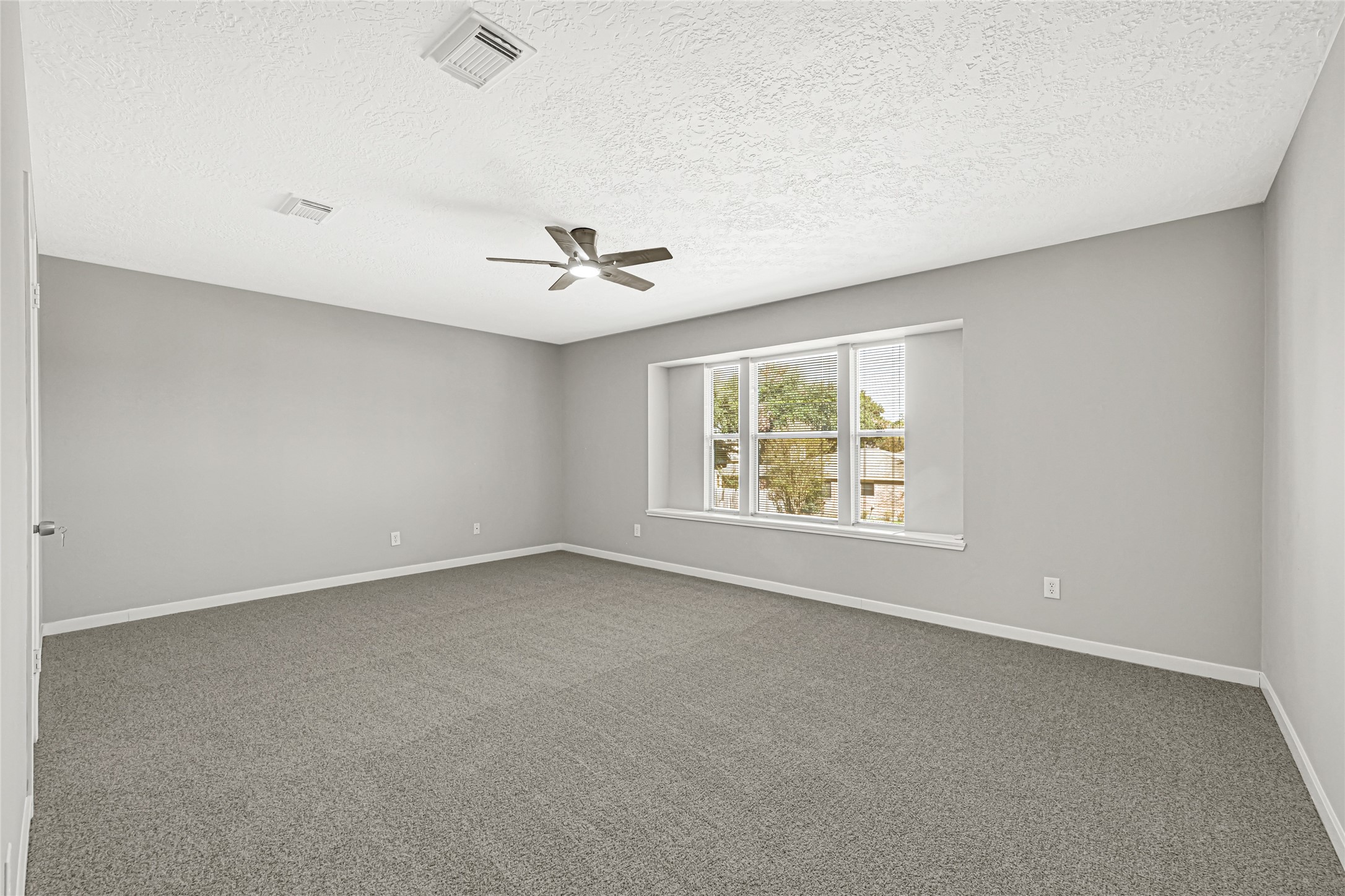 Generously sized primary bedroom with upgraded carpet and ceiling fan