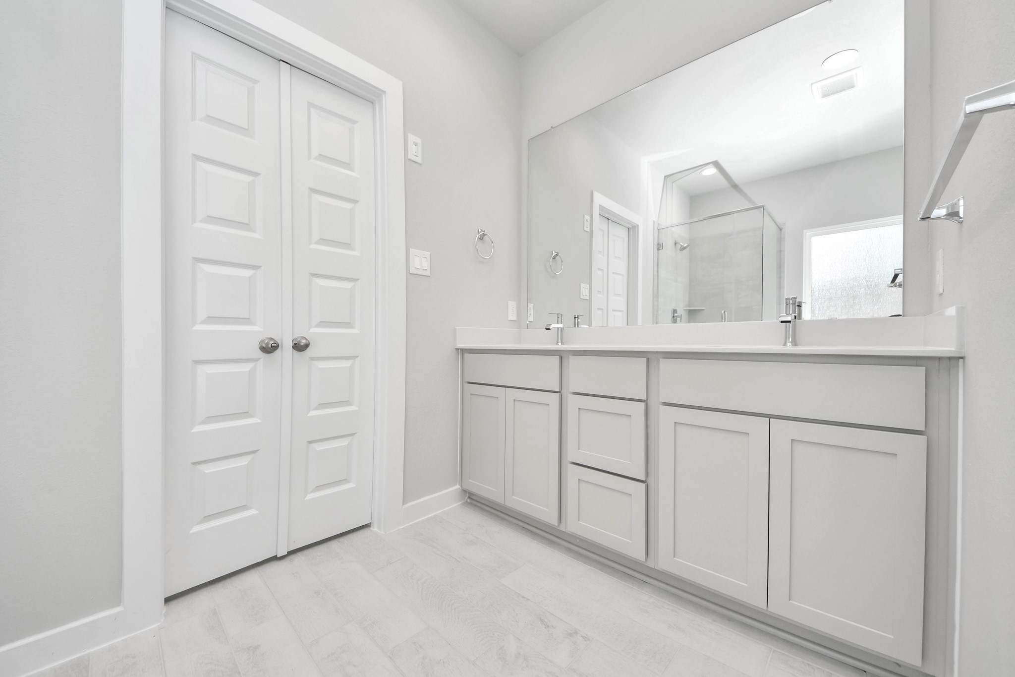 Elevate your daily routine at the elegant vanity, now equipped with double sinks, light countertops, modern hardware, and beautiful recessed lights. v