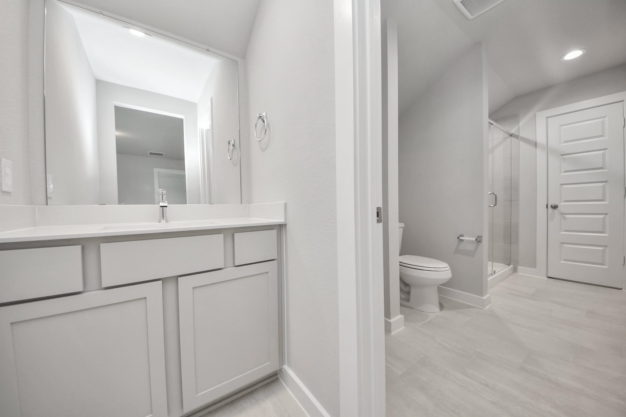 Experience convenience in the secondary bathroom, designed for Jack and Jill arrangements, now with a separate vanity area. This well-appointed space showcases stylish tile flooring, a bath/shower combo with an elegant tile surround, and light-stained wood cabinets. The beautiful light countertop adds a touch of sophistication, combining functionality and aesthetics seamlessly. Sample photo of completed home with similar floor plan. Actual colors and selections may vary.