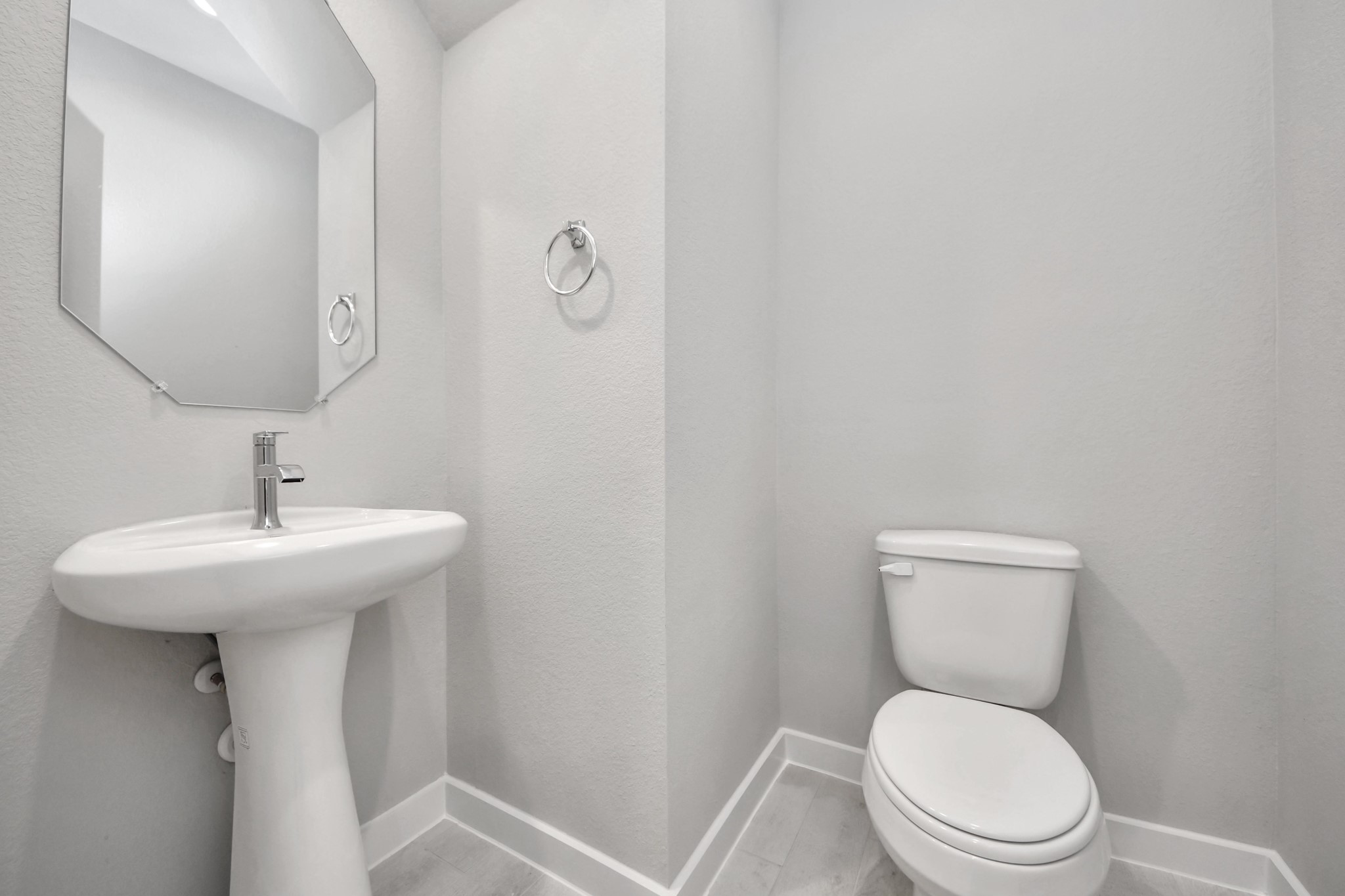This half bathroom features a stylish pedestal sink, modern hardware, and bright recessed lighting, creating a sleek and inviting space. Sample photo of completed home with similar floor plan. Actual colors and selections may vary. This half bathroom features a stylish pedestal sink, modern hardware, and bright recessed lighting, creating a sleek and inviting space. Sample photo of completed home with similar floor plan. Actual colors and selections may vary.