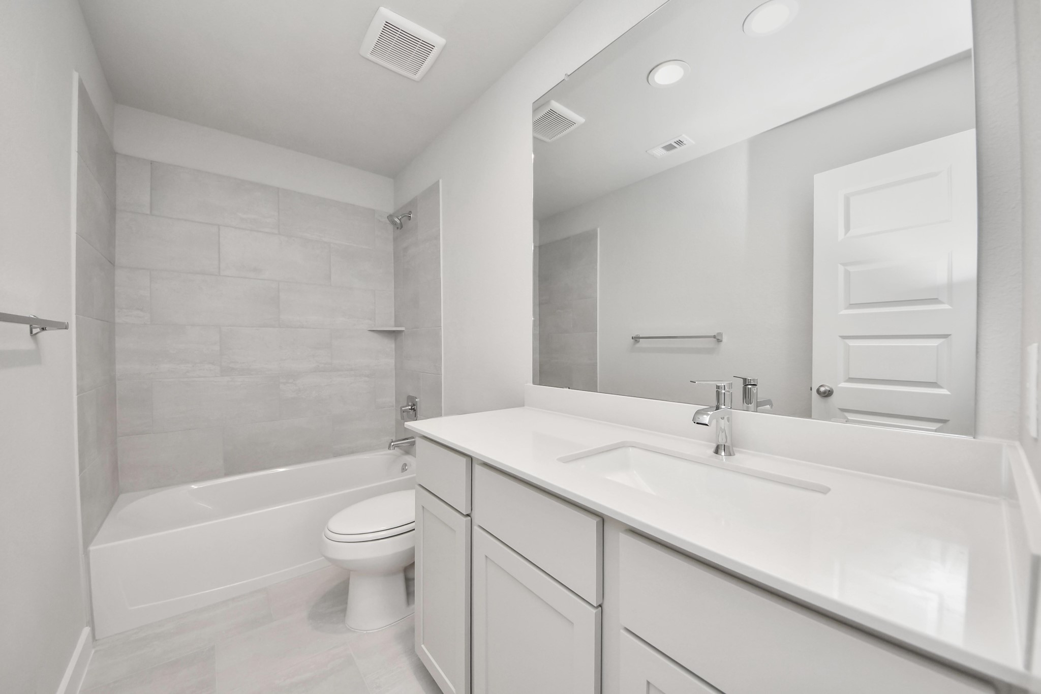 Secondary bath features tile flooring, bath/shower combo with tile surround, light stained wood cabinets, beautiful light countertop. Sample photo of completed home with similar floor plan. Actual colors and selections may vary.