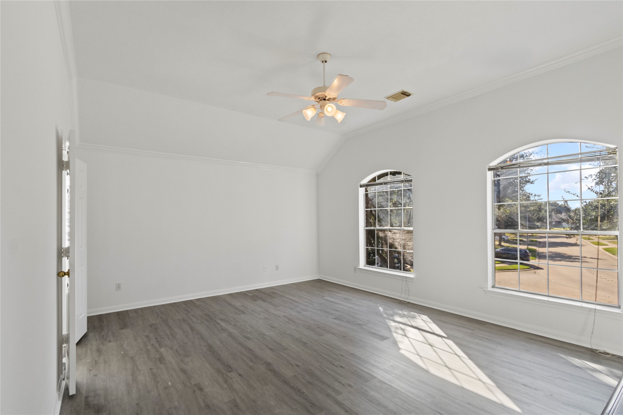 Spacious primary bedroom featuring vaulted ceilings, elegant arched windows, abundant natural light, and modern flooring for a bright and inviting retreat.